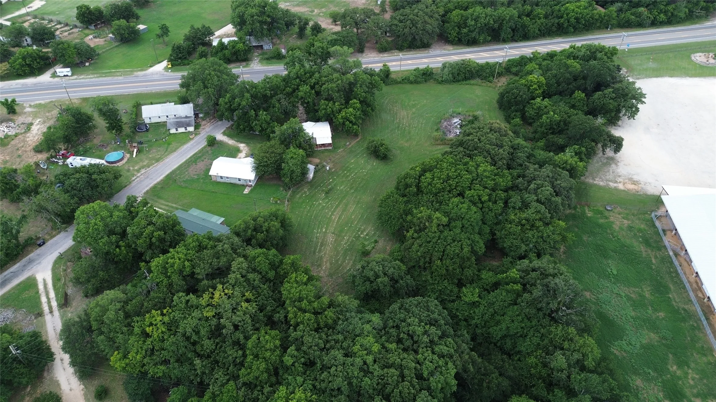 Expansive green land with multiple structures and mature trees