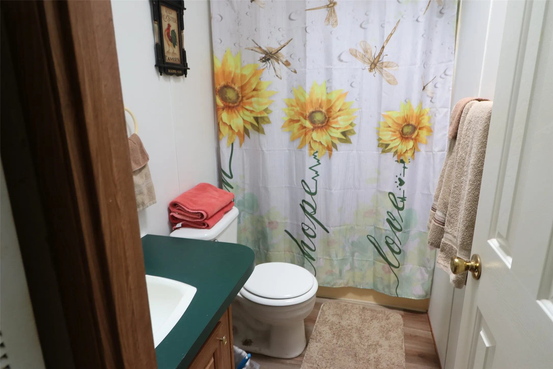 Bathroom featuring a white toilet, white vanity sink, dark green countertop, and wood-finish cabinetry