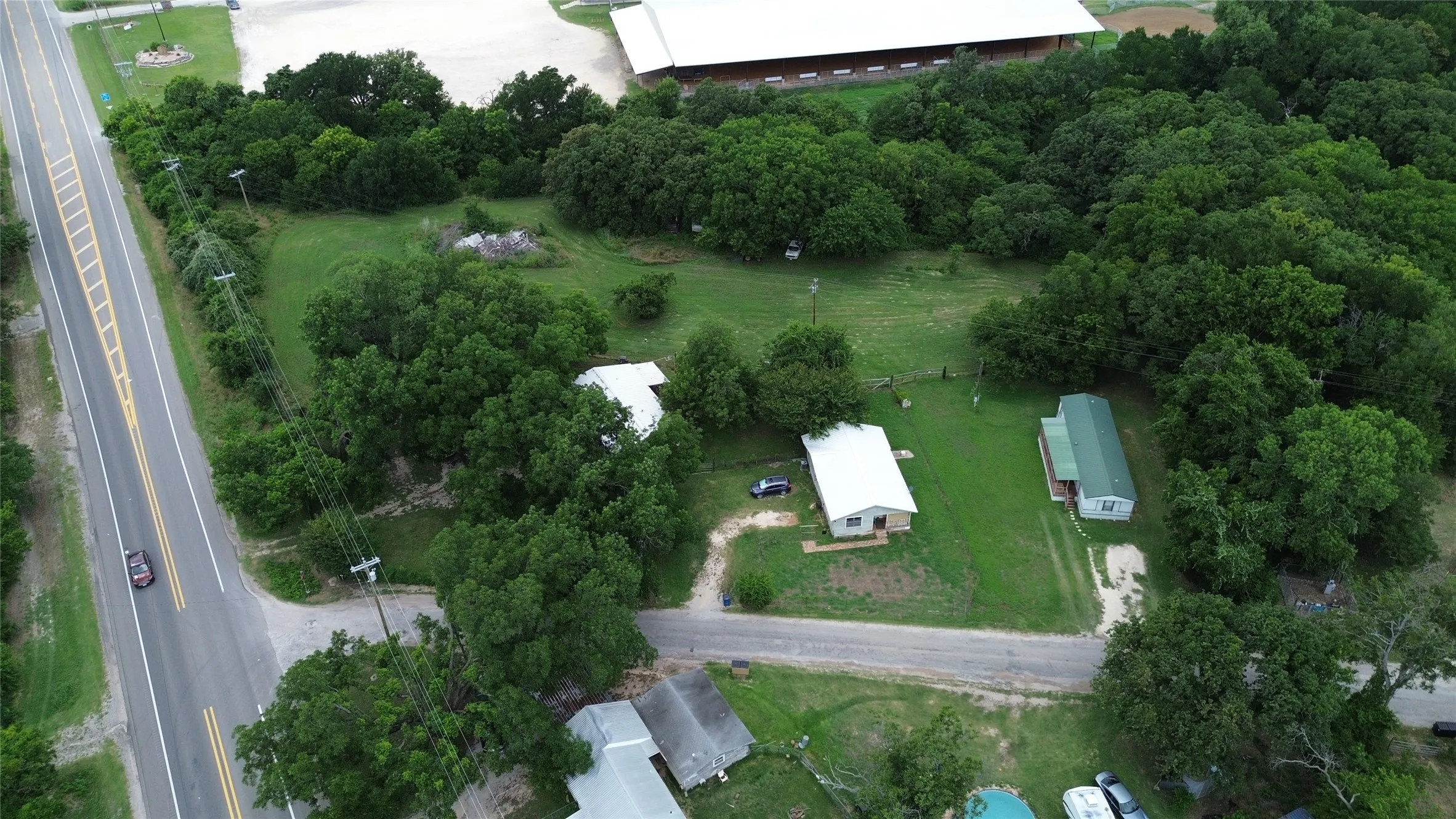 Expansive treed lot featuring two residential structures and a large open field