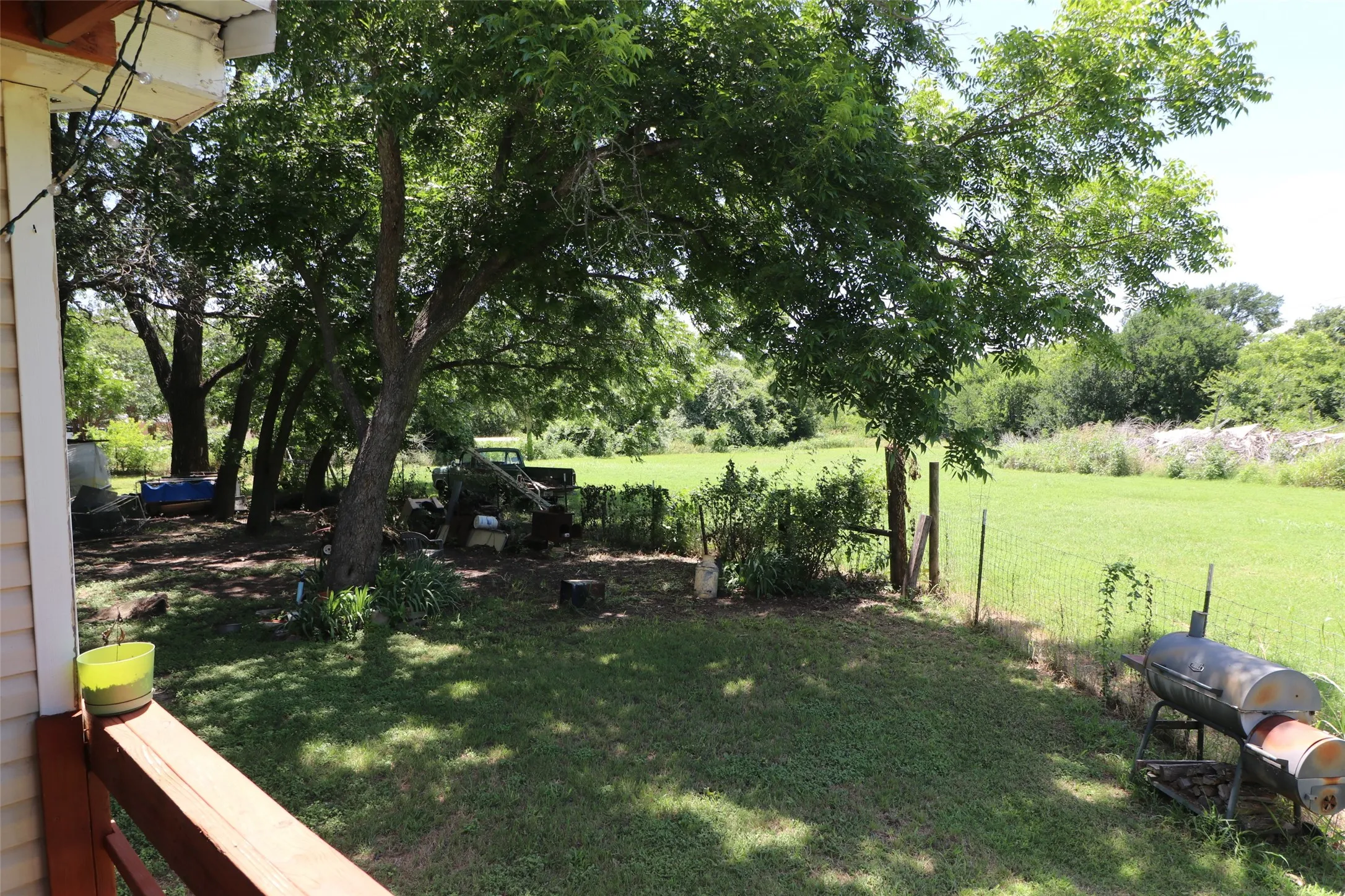 Expansive exterior grounds featuring mature trees, a grassy lawn, and a perimeter fence