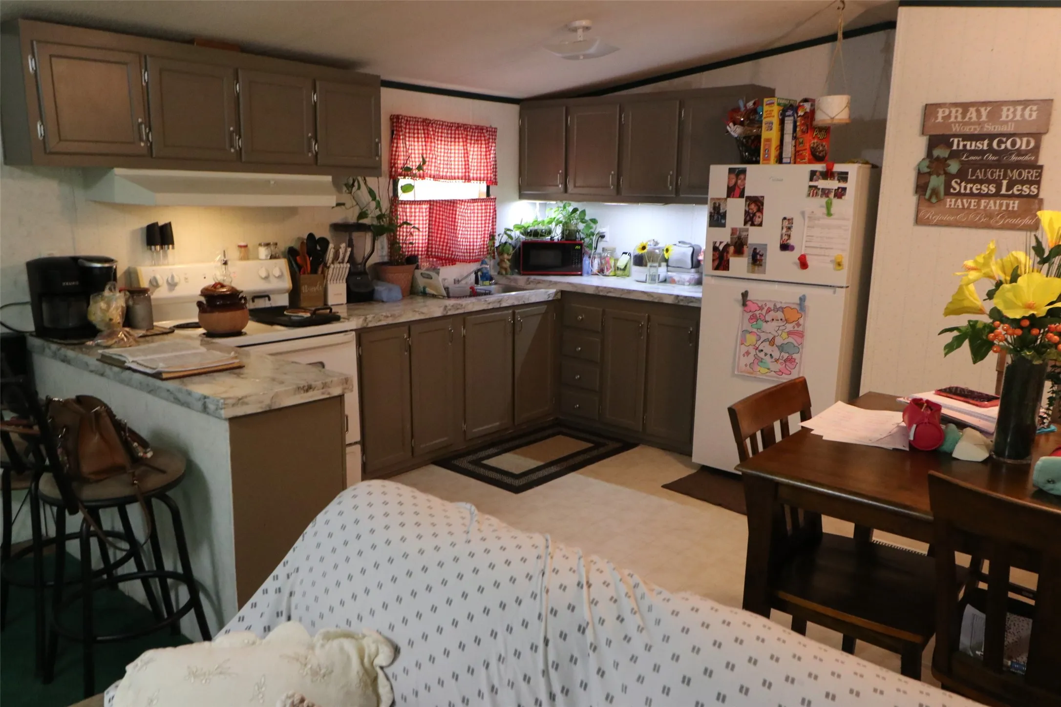 Kitchen featuring L-shaped countertops, ample cabinetry, built-in range, and refrigerator