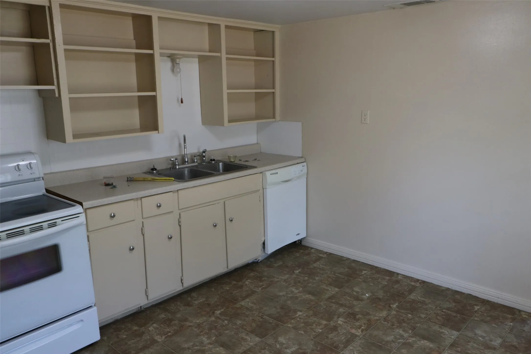 Kitchen featuring a double basin sink, white range, white dishwasher, upper open shelving, and lower cabinetry