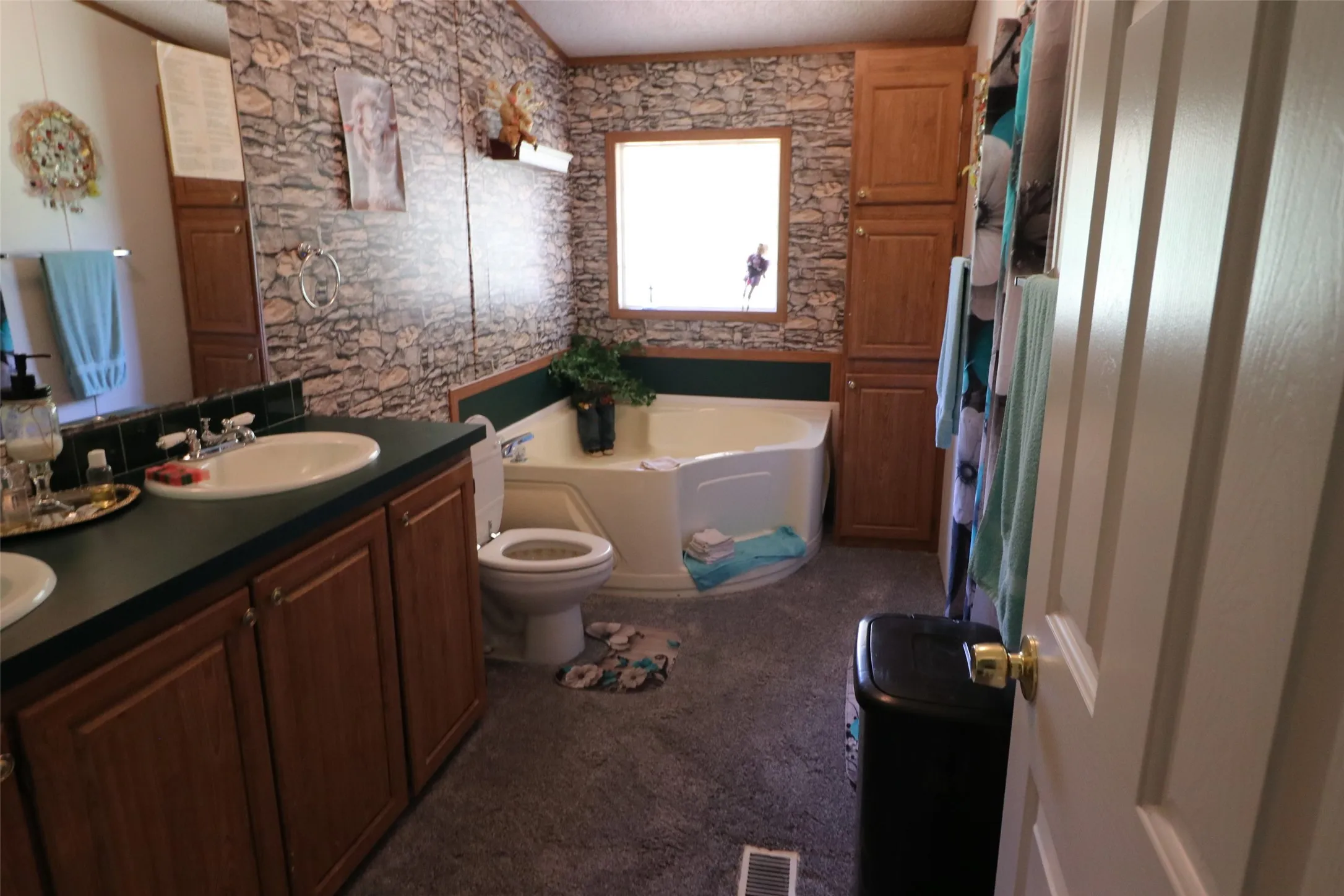 Bathroom featuring a corner soaking tub, double vanity with integrated sinks, wood-finish cabinetry, and built-in vertical storage