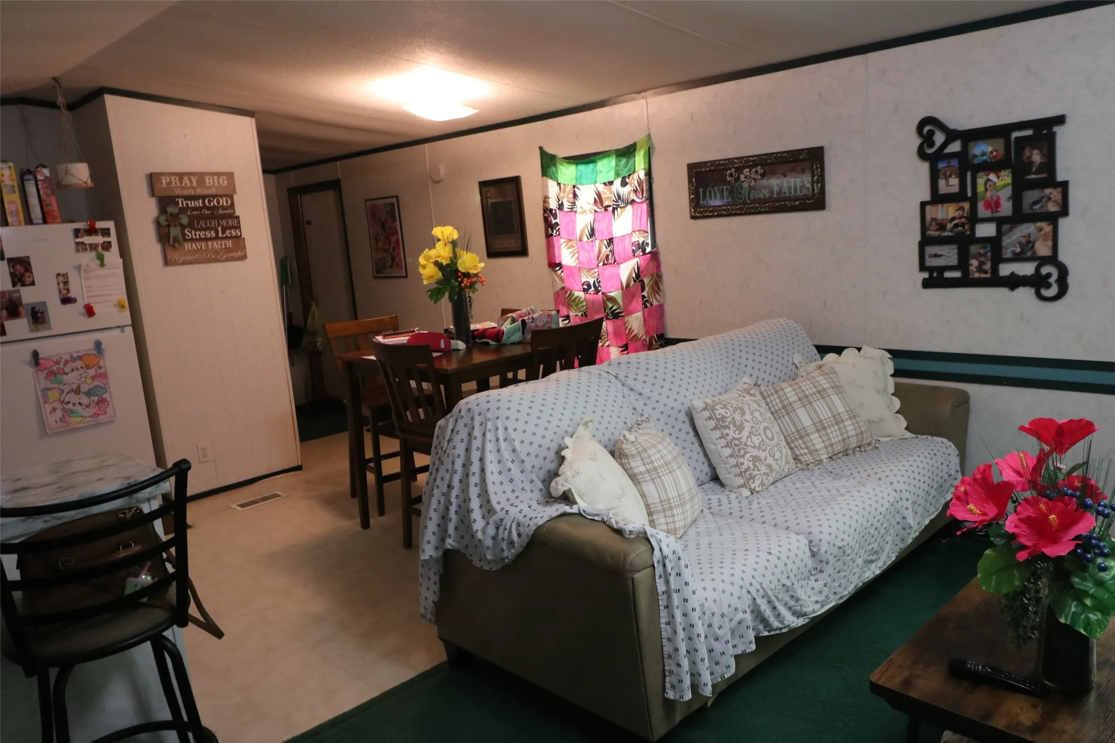 Open concept living space featuring neutral wall paneling with a contrasting green trim, recessed ceiling lighting, and hard surface flooring in a light tone