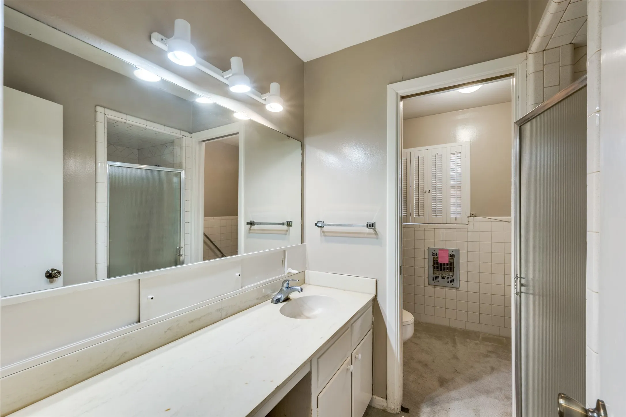 Bathroom featuring an extended vanity with an integrated sink, built-in cabinetry, a track lighting fixture, and a tiled shower enclosure