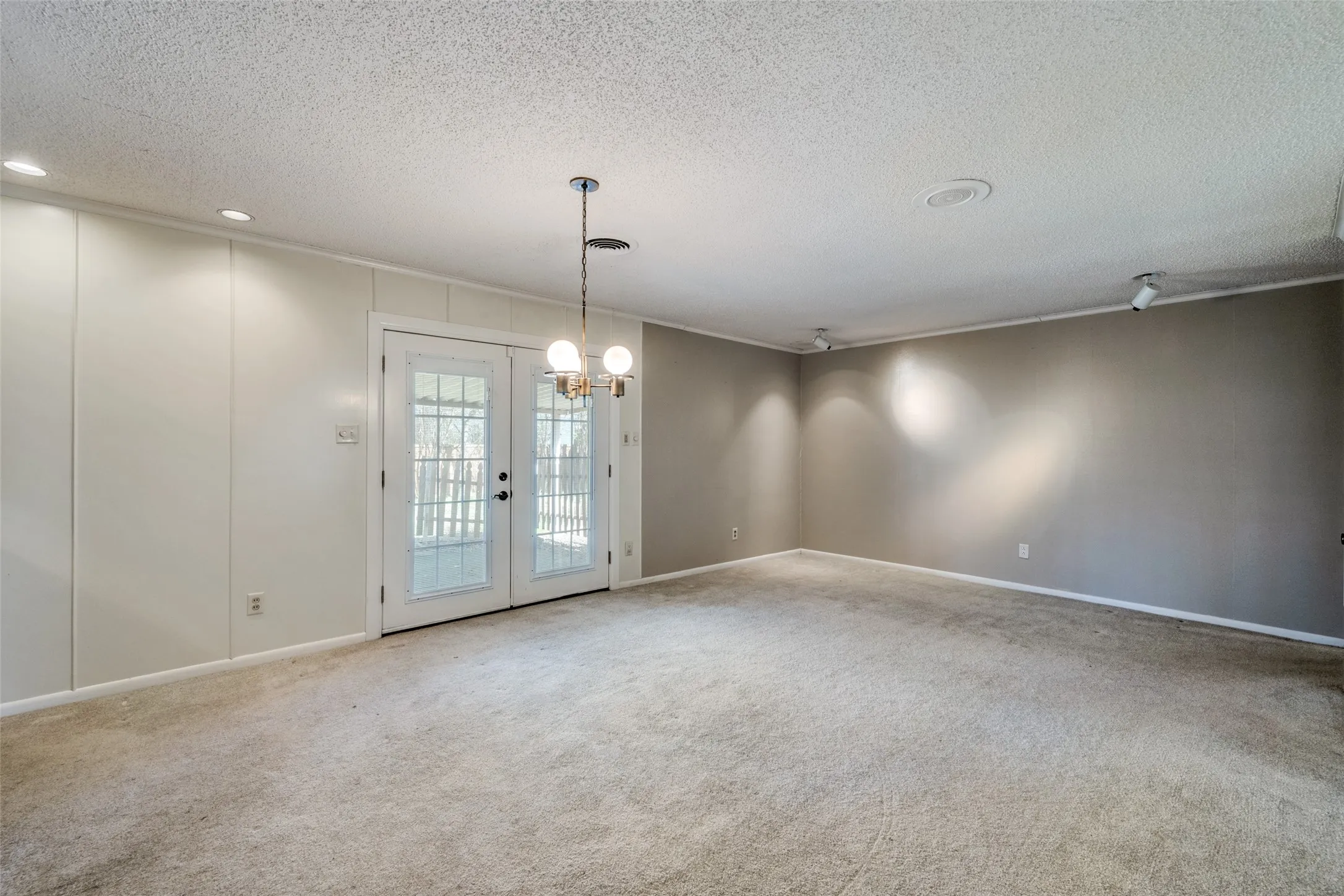 Spacious room featuring broadloom carpeting and a chandelier lighting fixture