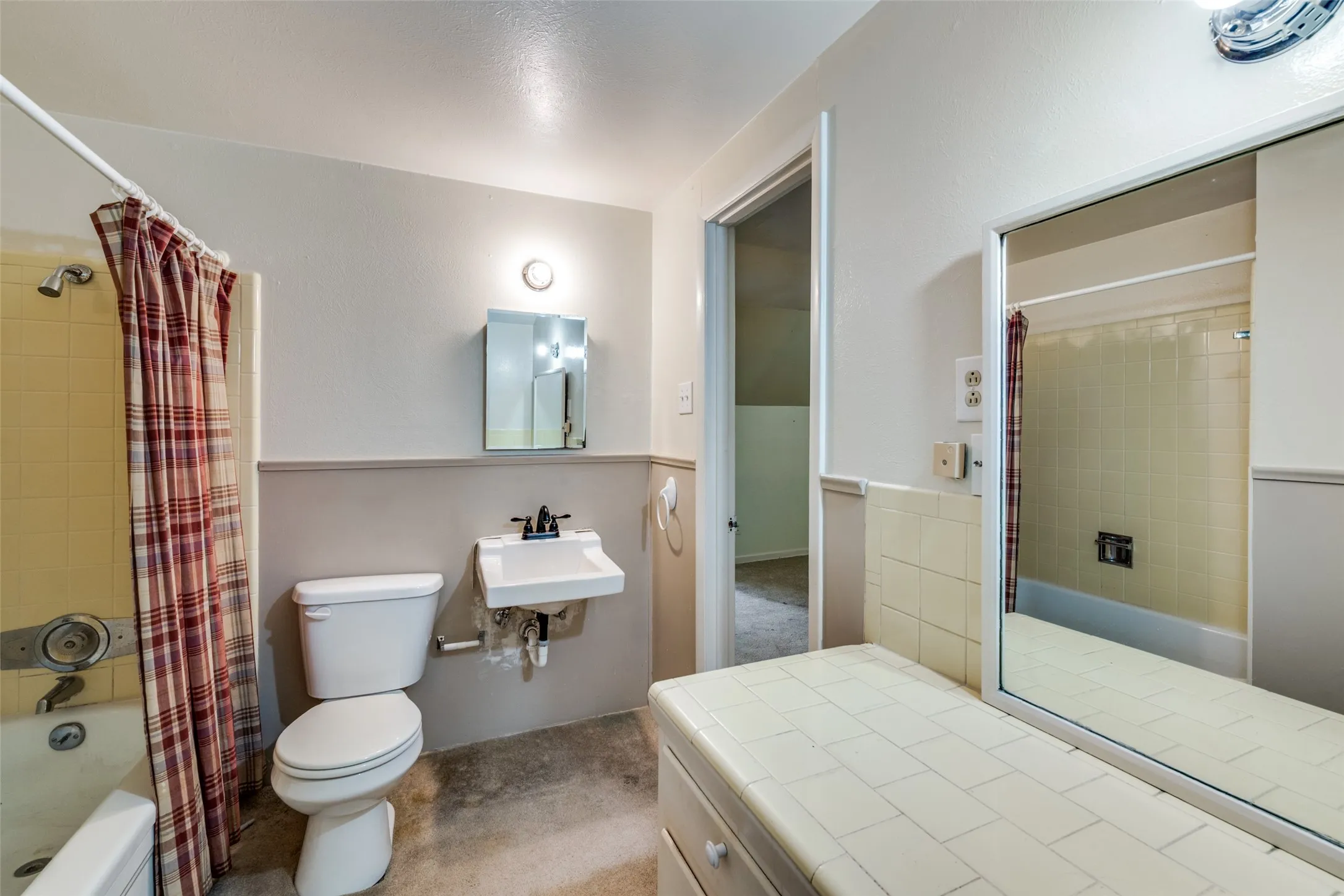 Bathroom featuring a wall-mounted sink, toilet, and a bathtub with integrated shower
