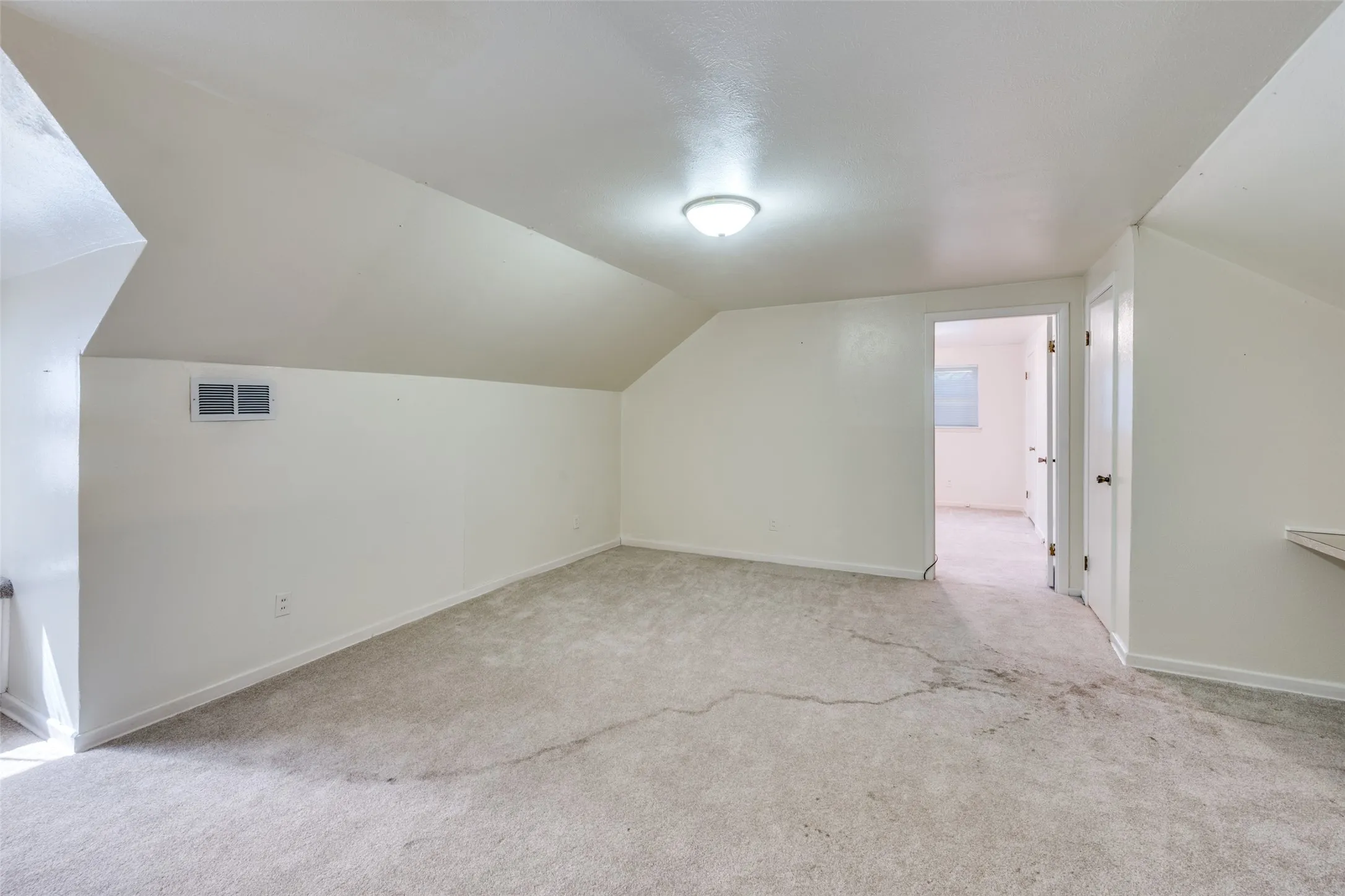 Carpeted room featuring a sloped ceiling and white walls