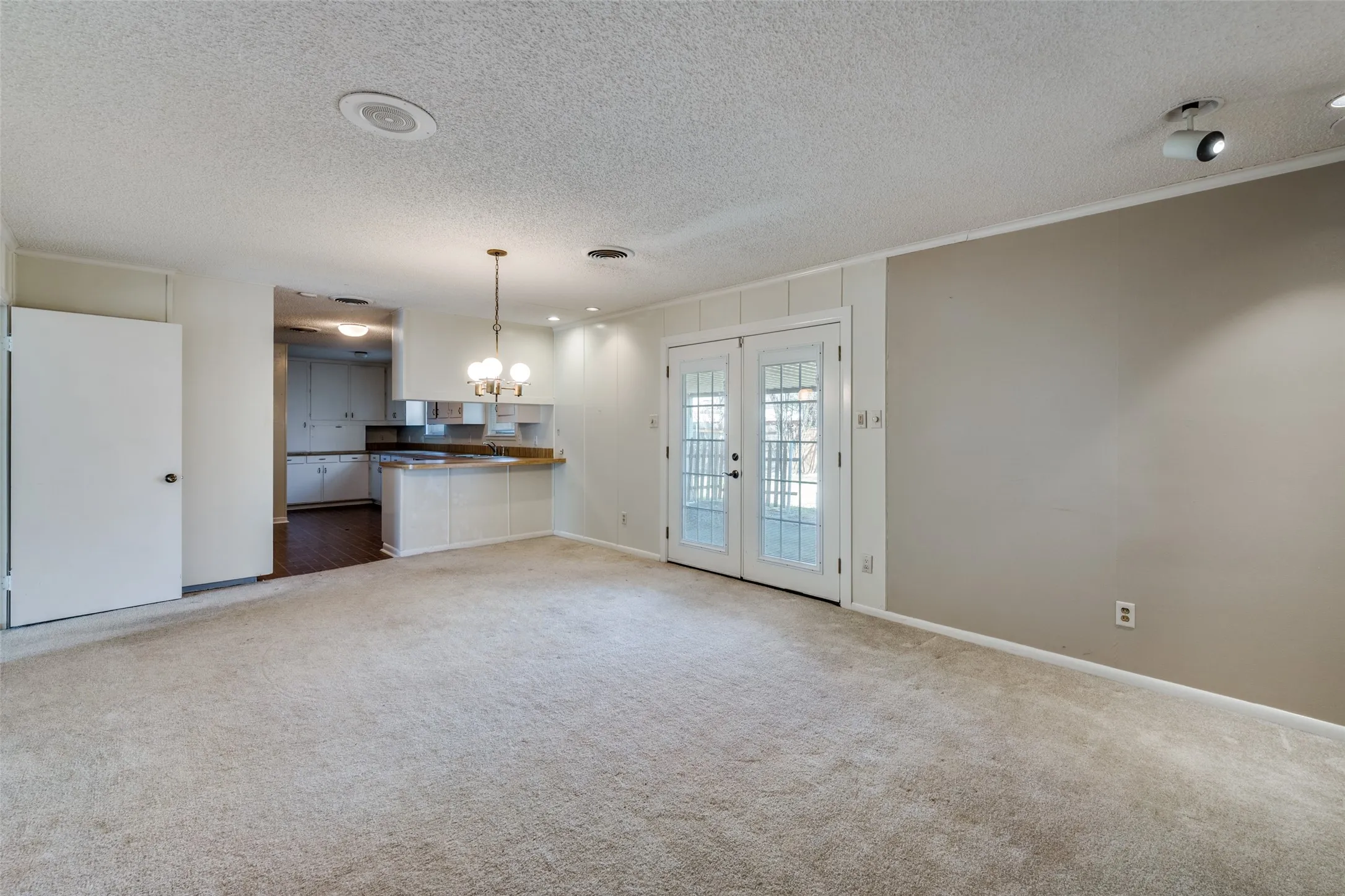 Carpeted living area with textured ceiling, recessed lighting, and track lighting fixtures