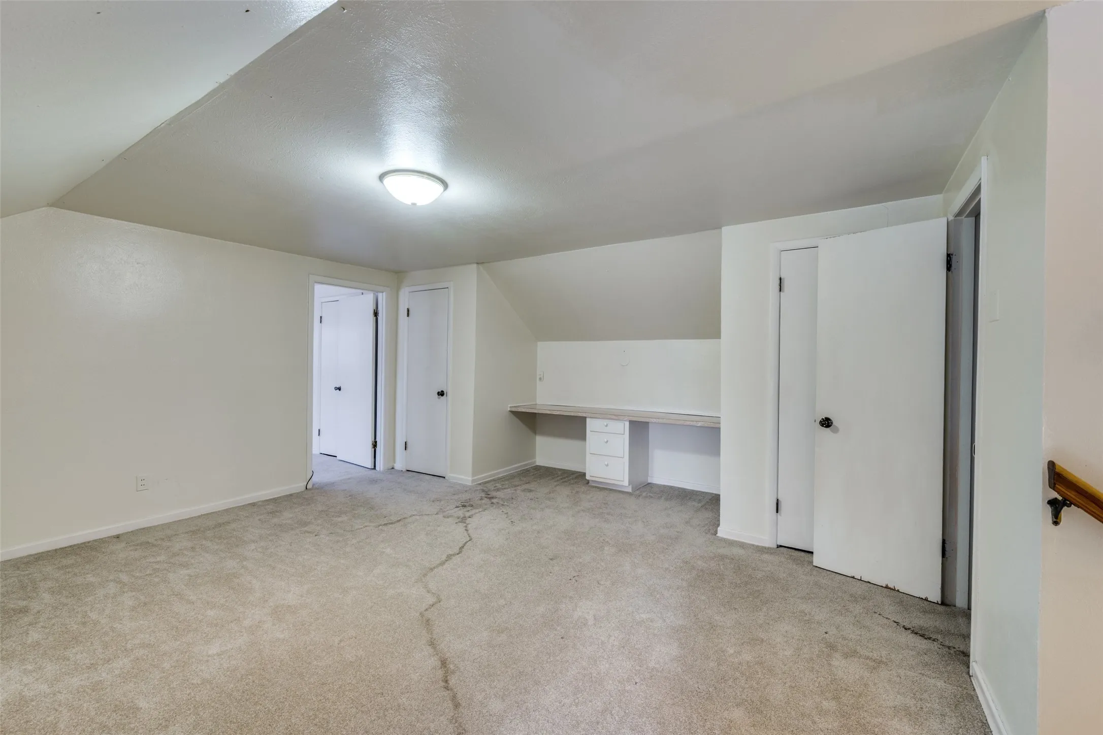 Carpeted room featuring a built-in desk with drawers, white painted walls, and a semi-flush mount ceiling light