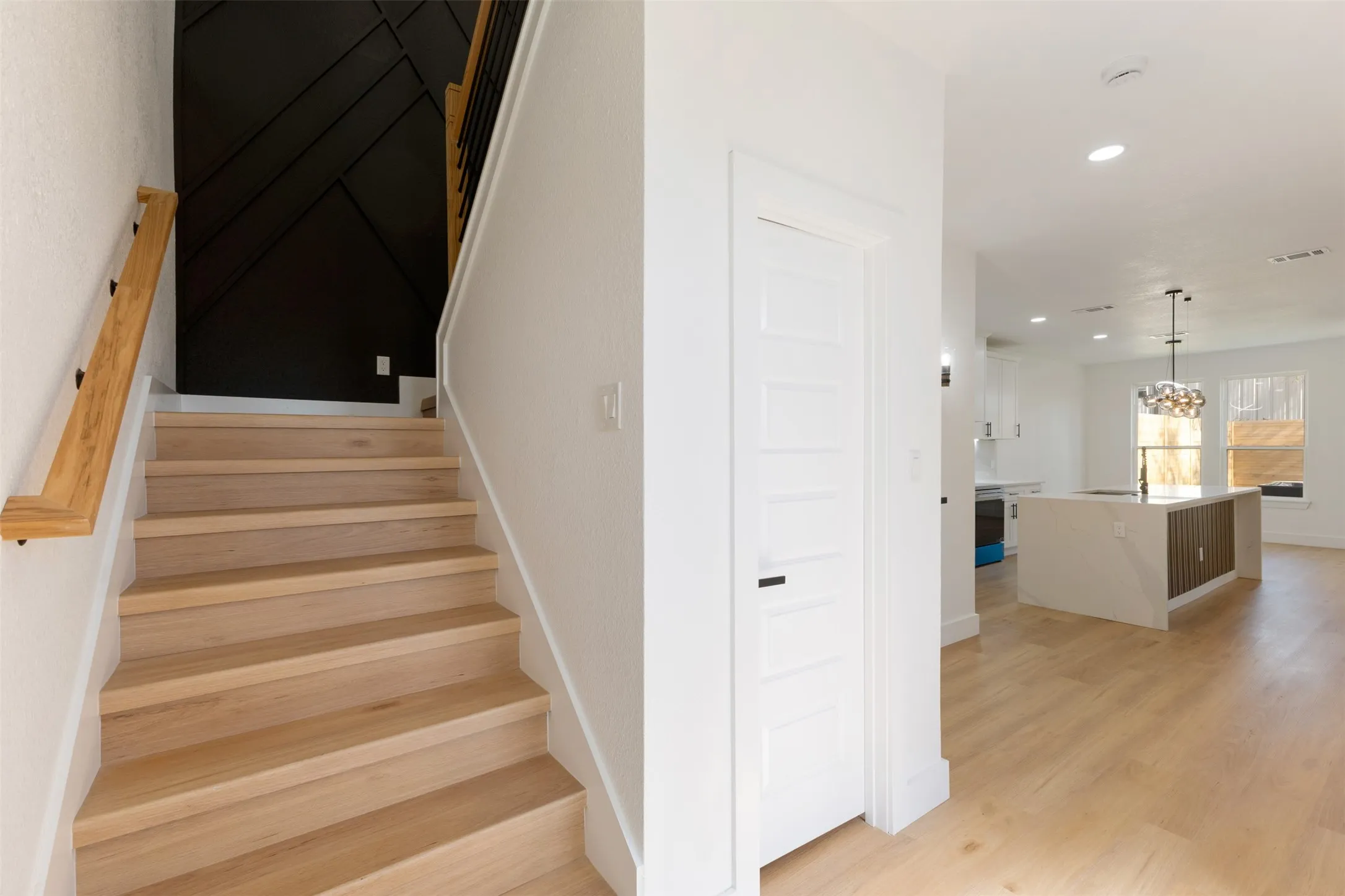 Stairs with wood finished floors and hanging lights