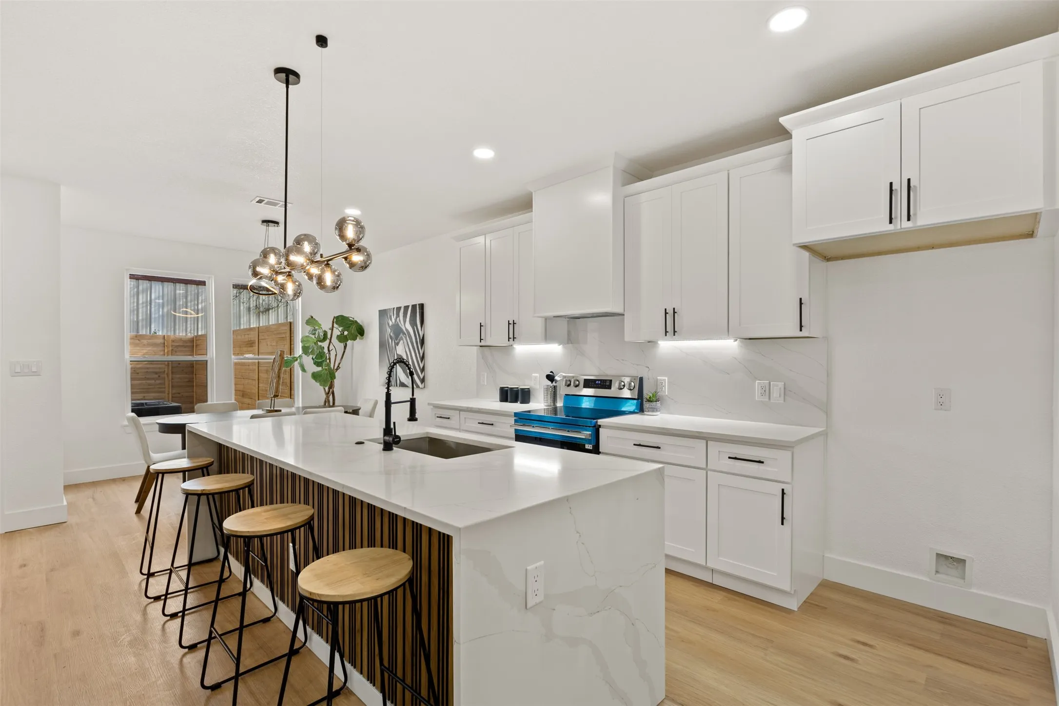 Kitchen with white cabinets, a kitchen breakfast bar, stainless steel electric range oven, and light wood-style floors