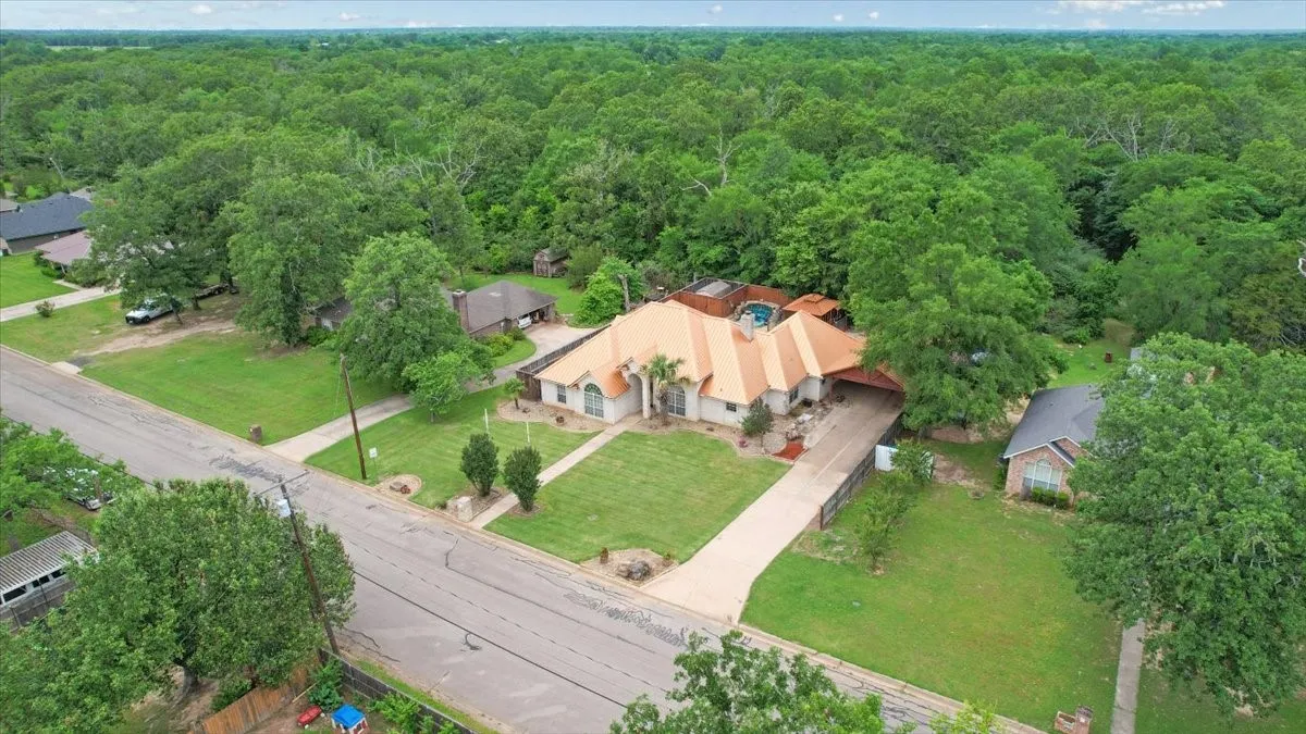 Expansive property featuring a unique multi-gabled roofline, a large driveway, and mature landscaping