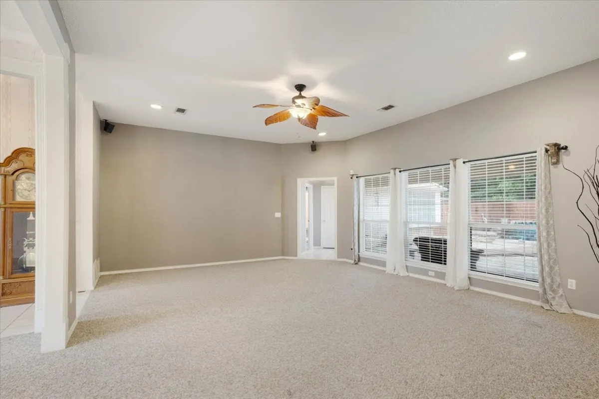 Spacious living area featuring neutral carpeting and recessed lighting.