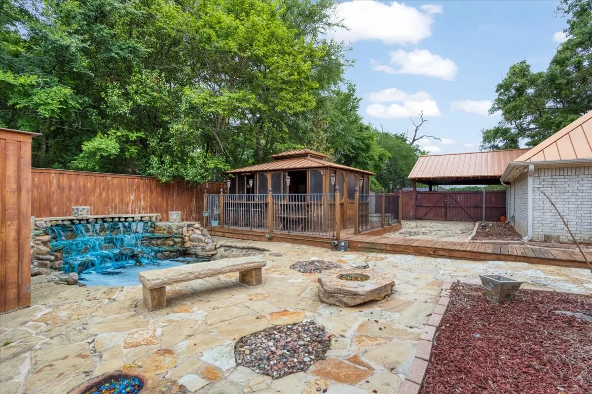 Expansive flagstone patio with a rock waterfall feature, a stone bench, and built-in fire pits.