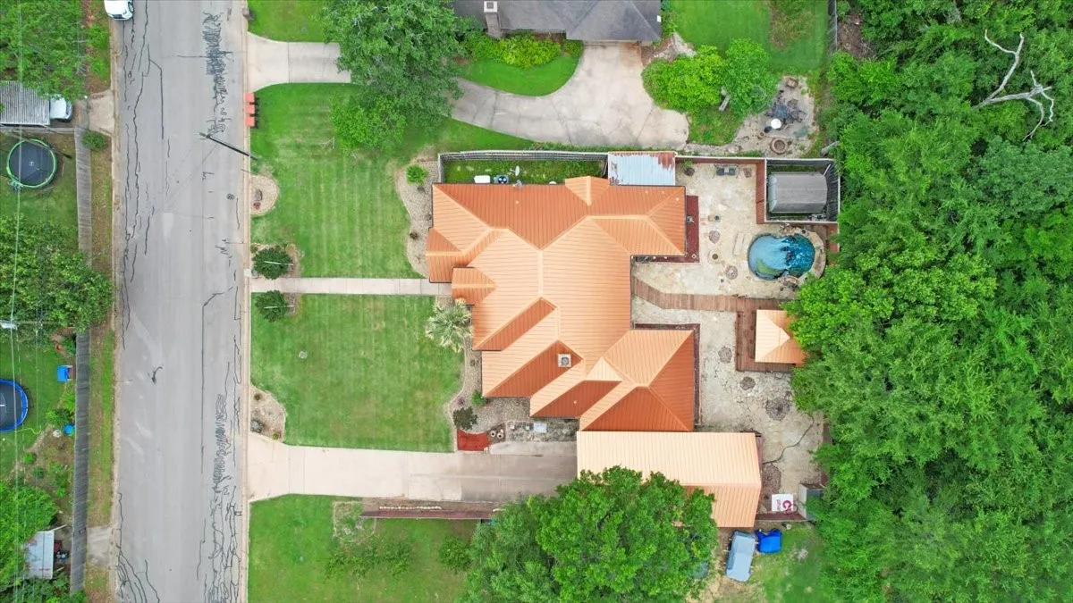 Property featuring a red tile roof, extensive stone patio, and a built-in swimming pool