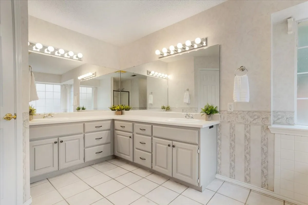 Spacious bathroom featuring an expansive L-shaped vanity with dual sinks and multiple mirrors.