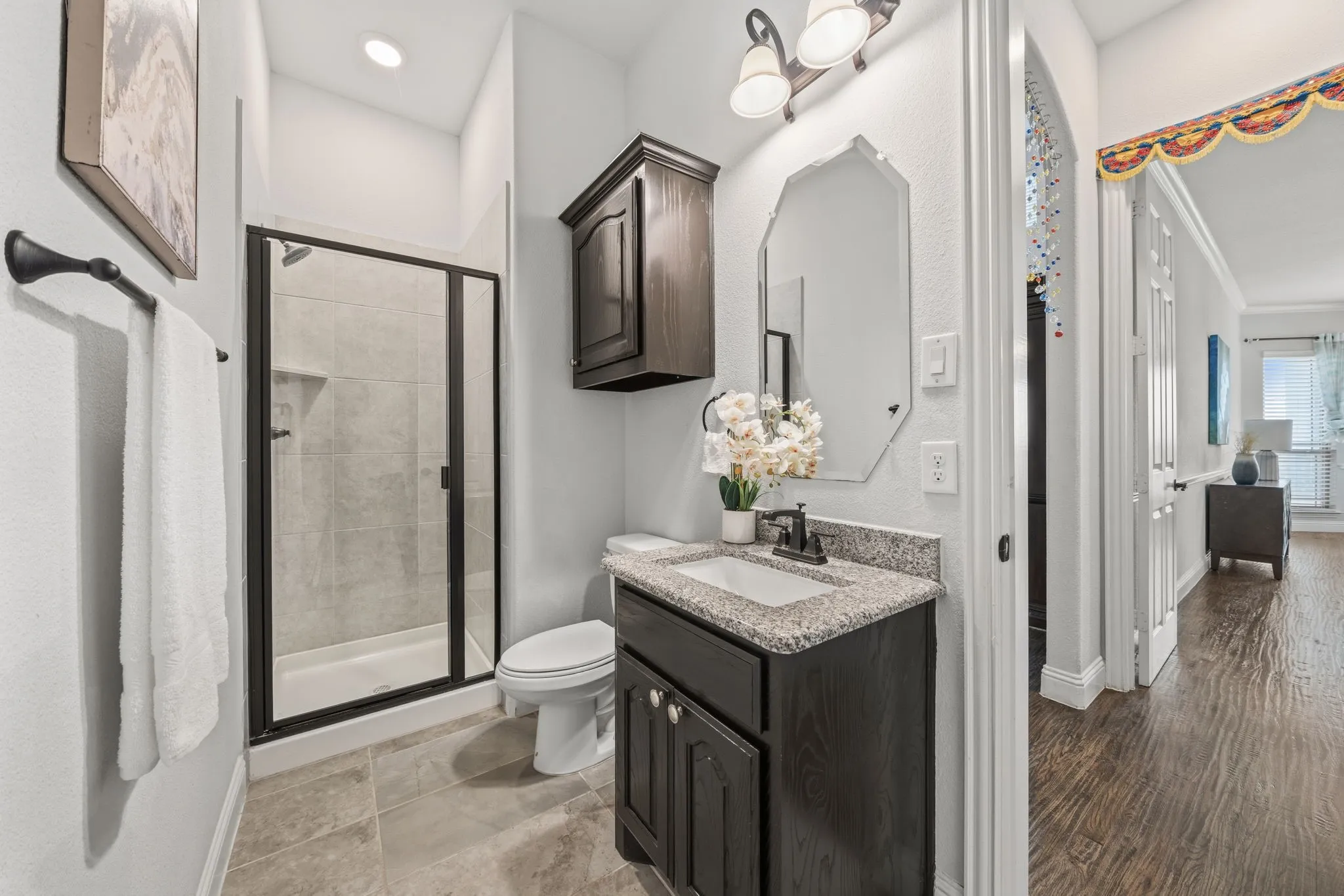 Bathroom featuring a dark wood-finish vanity with a granite countertop and an integrated sink