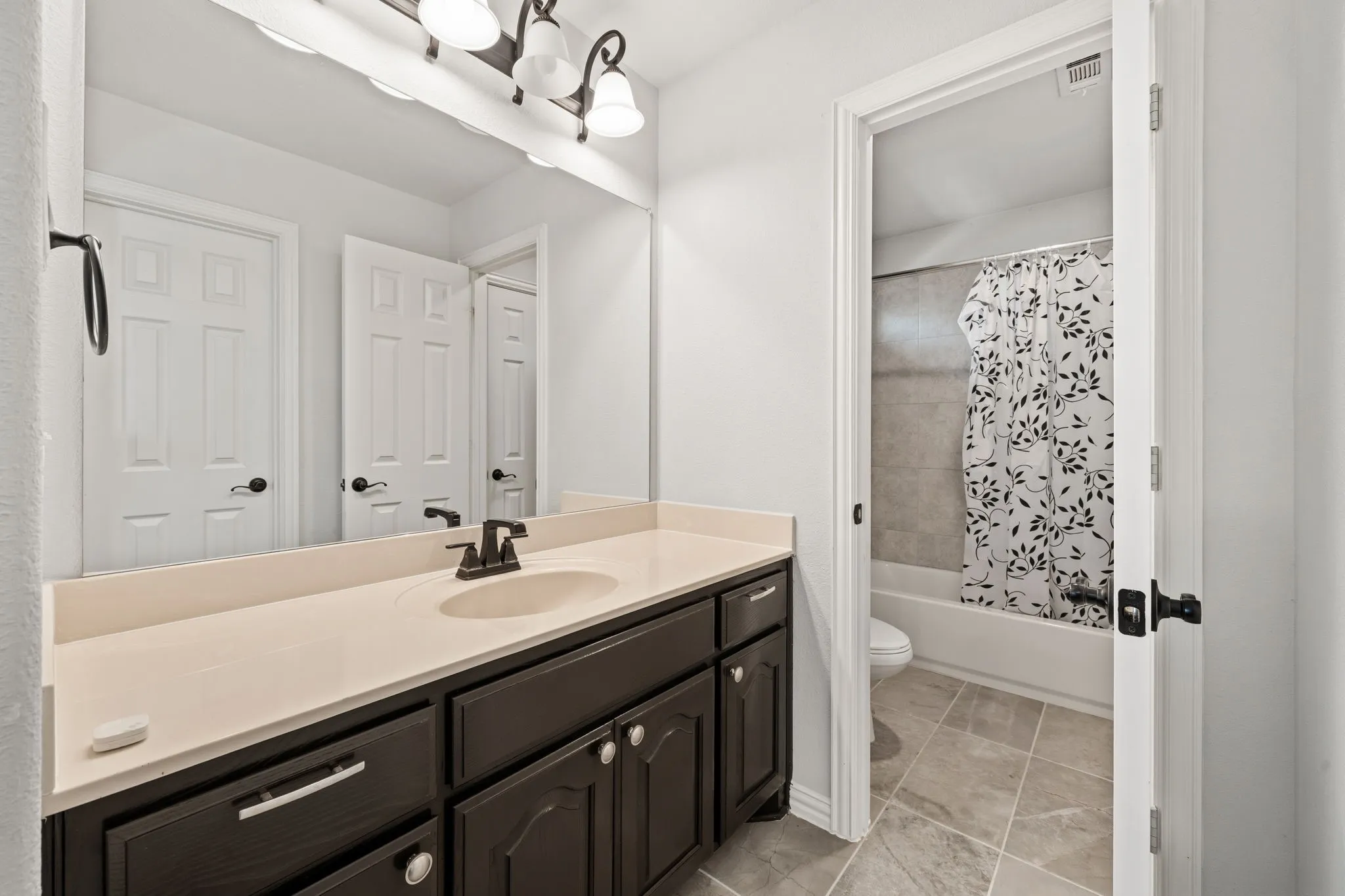 Bathroom vanity featuring a single undermount sink, dark cabinetry, and light-toned countertop