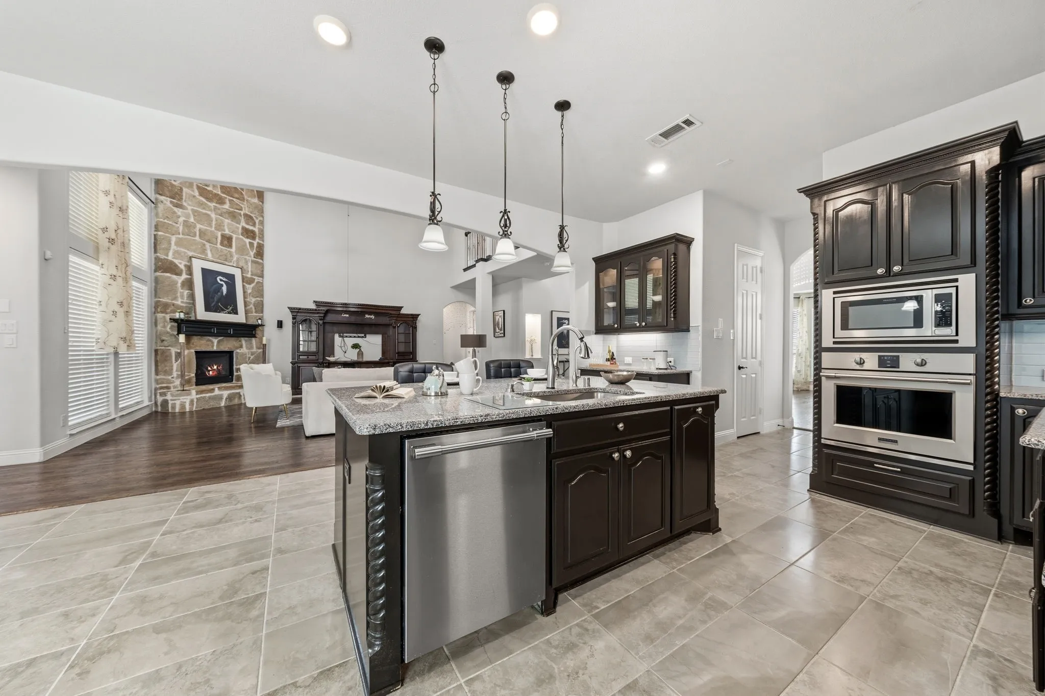 Kitchen island featuring a stainless steel dishwasher, undermount sink, and pendant lighting