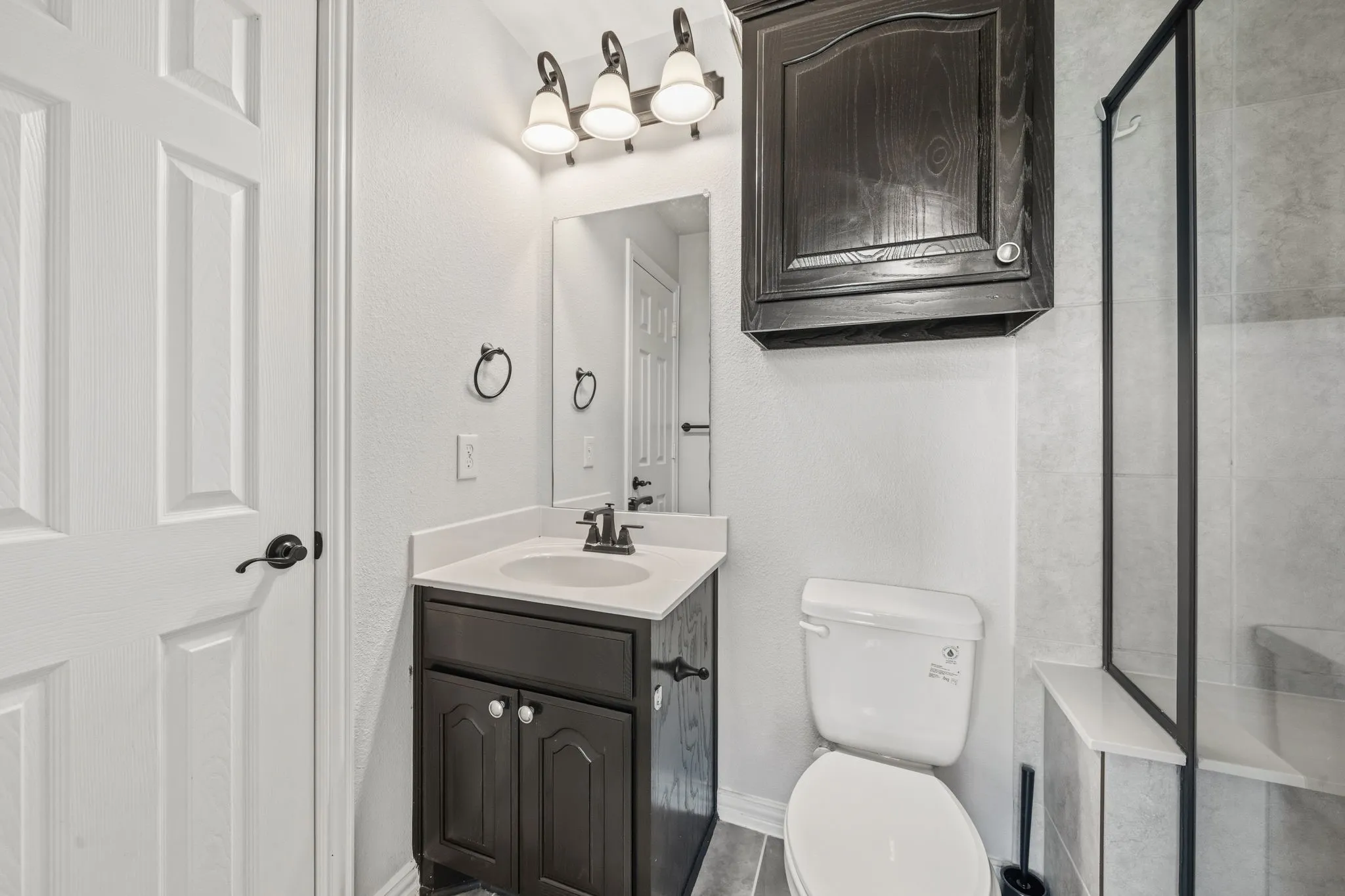 Bathroom vanity featuring a single sink, dark wood-finish cabinetry, and a countertop
