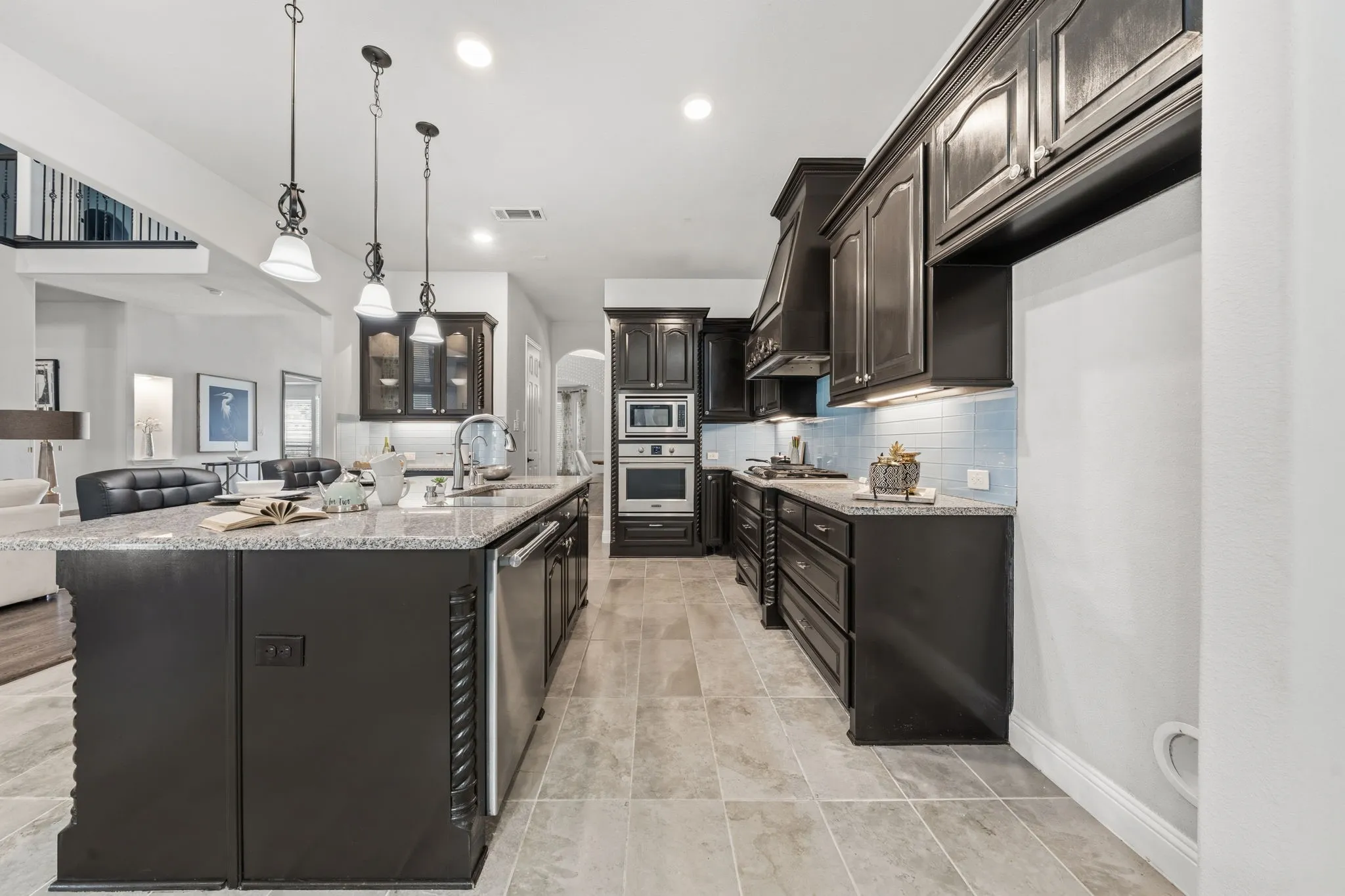 Gourmet kitchen featuring dark wood cabinetry, light-colored granite countertops, and a light blue tile backsplash
