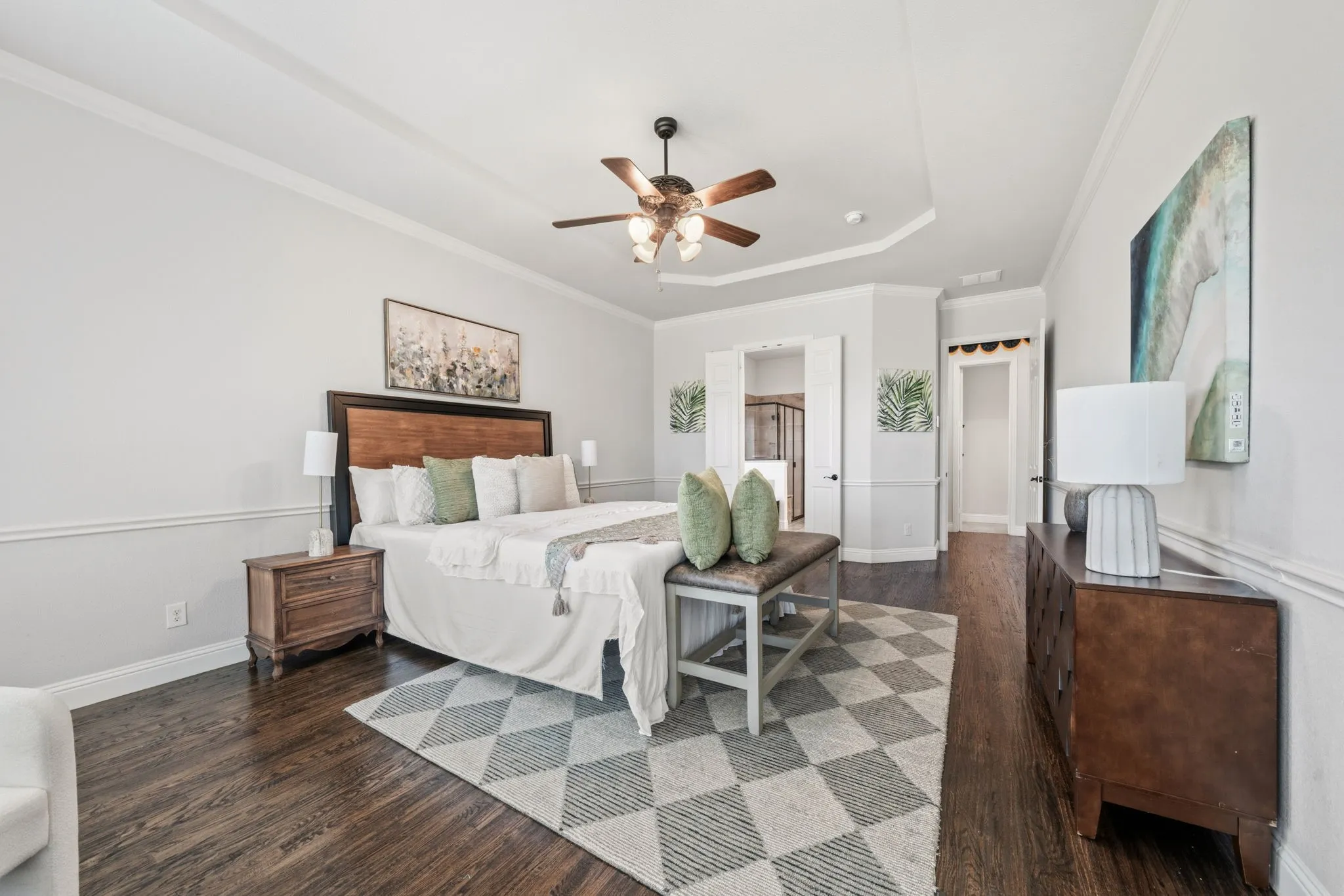 Spacious room featuring wood-finish flooring, a tray ceiling, crown molding, and wainscoting