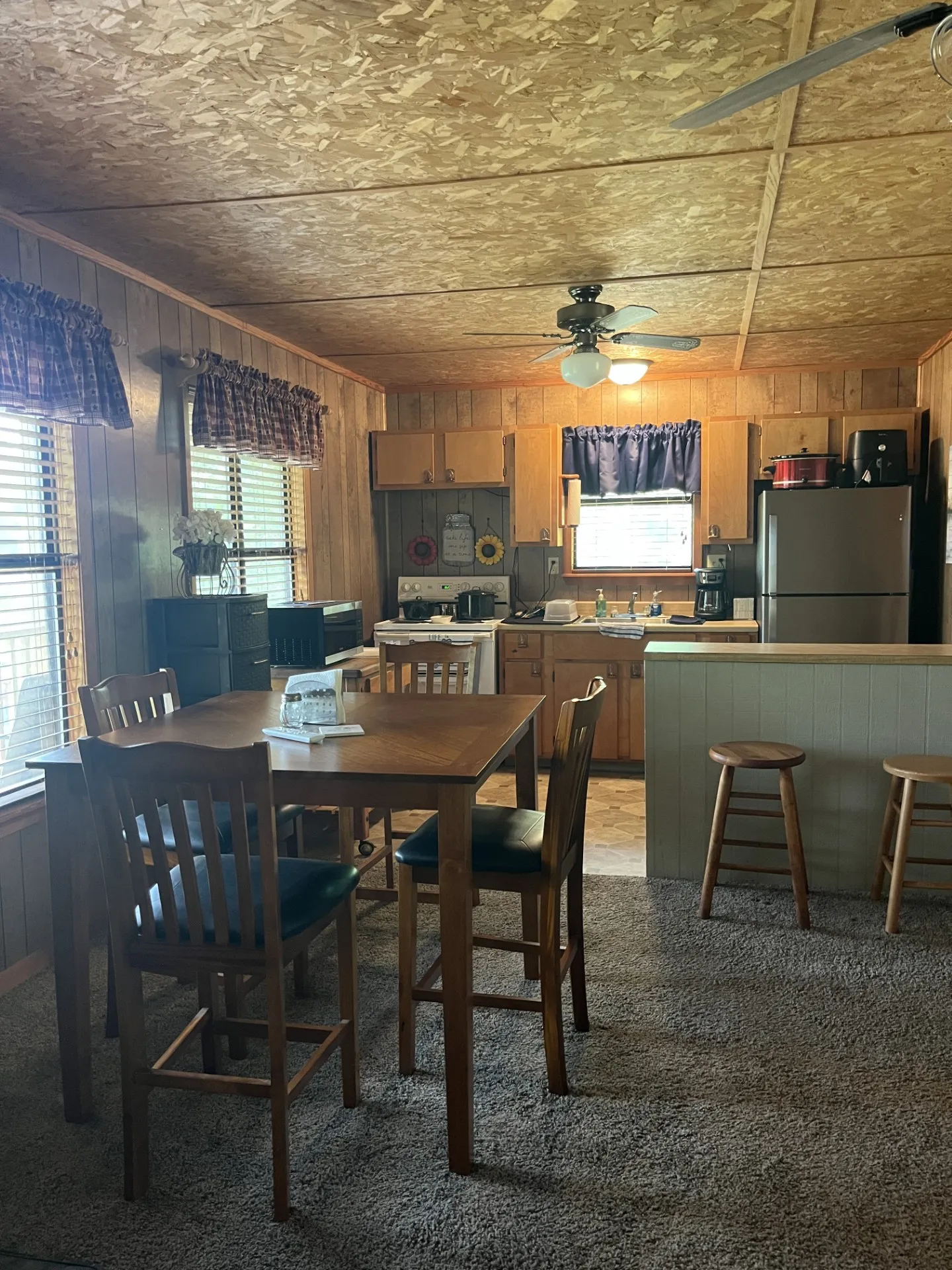 Kitchen and dining area featuring wood-paneled walls, a ceiling fan, and built-in wood cabinetry
