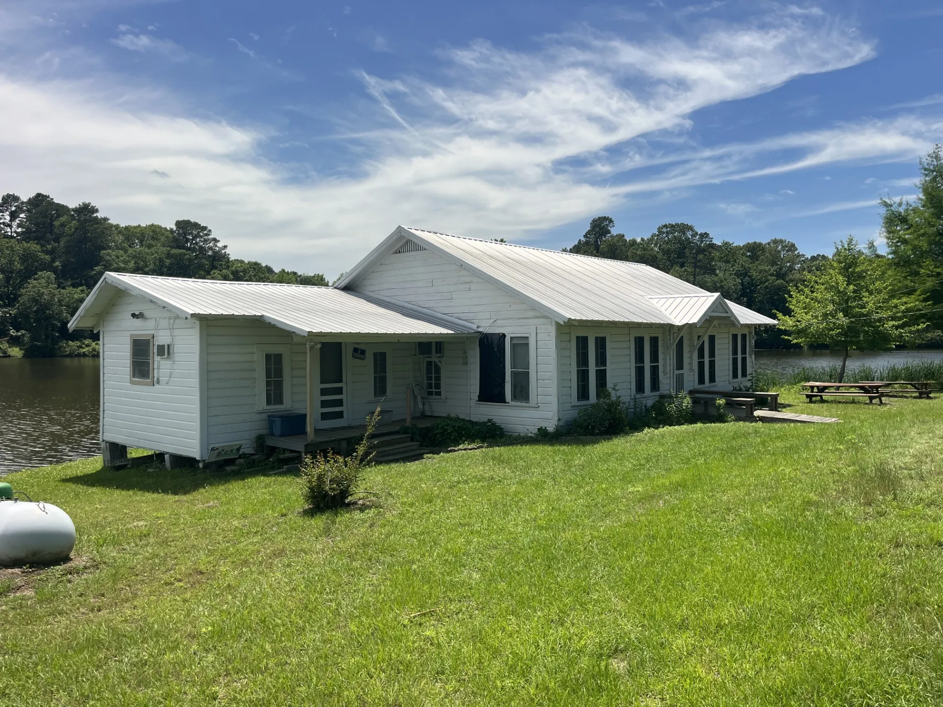 White siding structure with a metal roof directly on a body of water