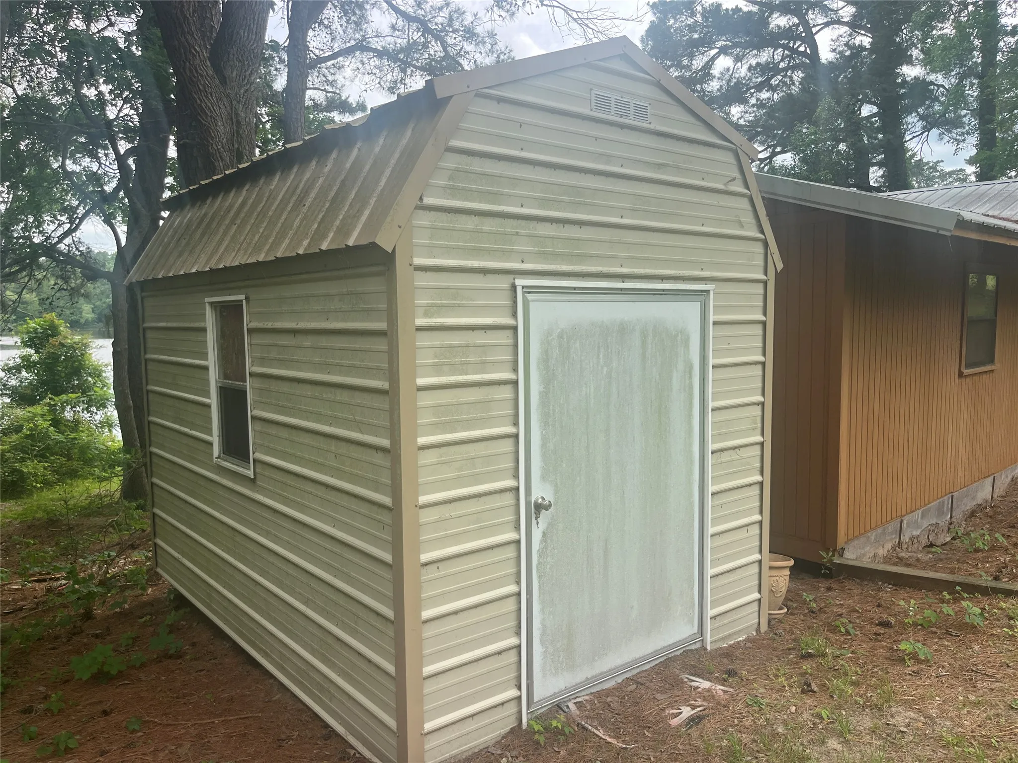 Detached storage shed featuring corrugated metal siding and a gambrel roof