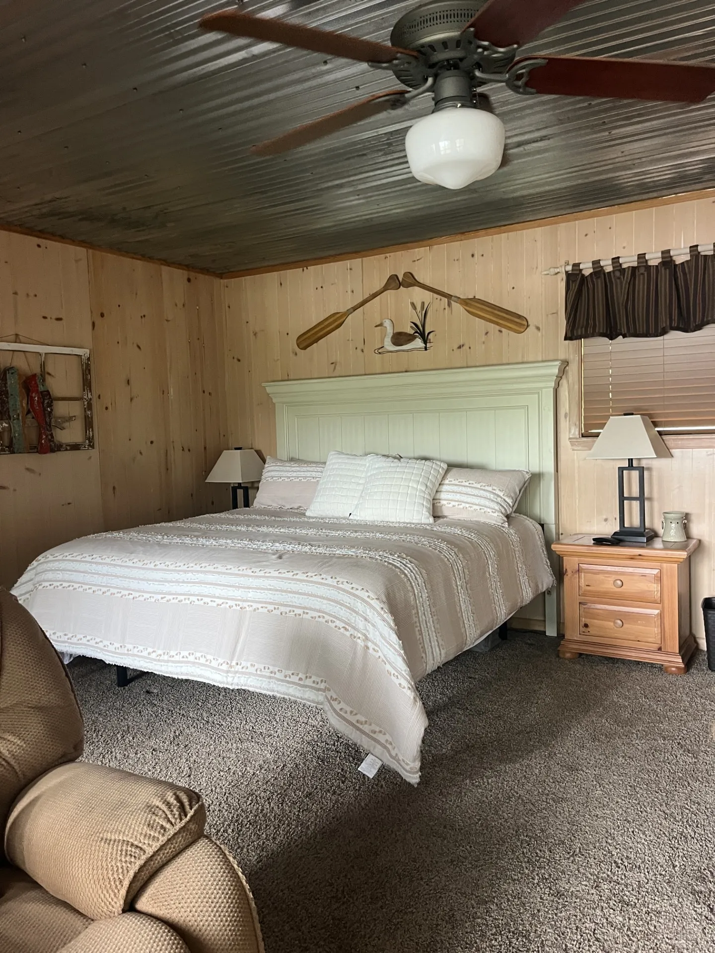 Interior room featuring wood paneling, a corrugated metal ceiling, and a ceiling fan with integrated lighting