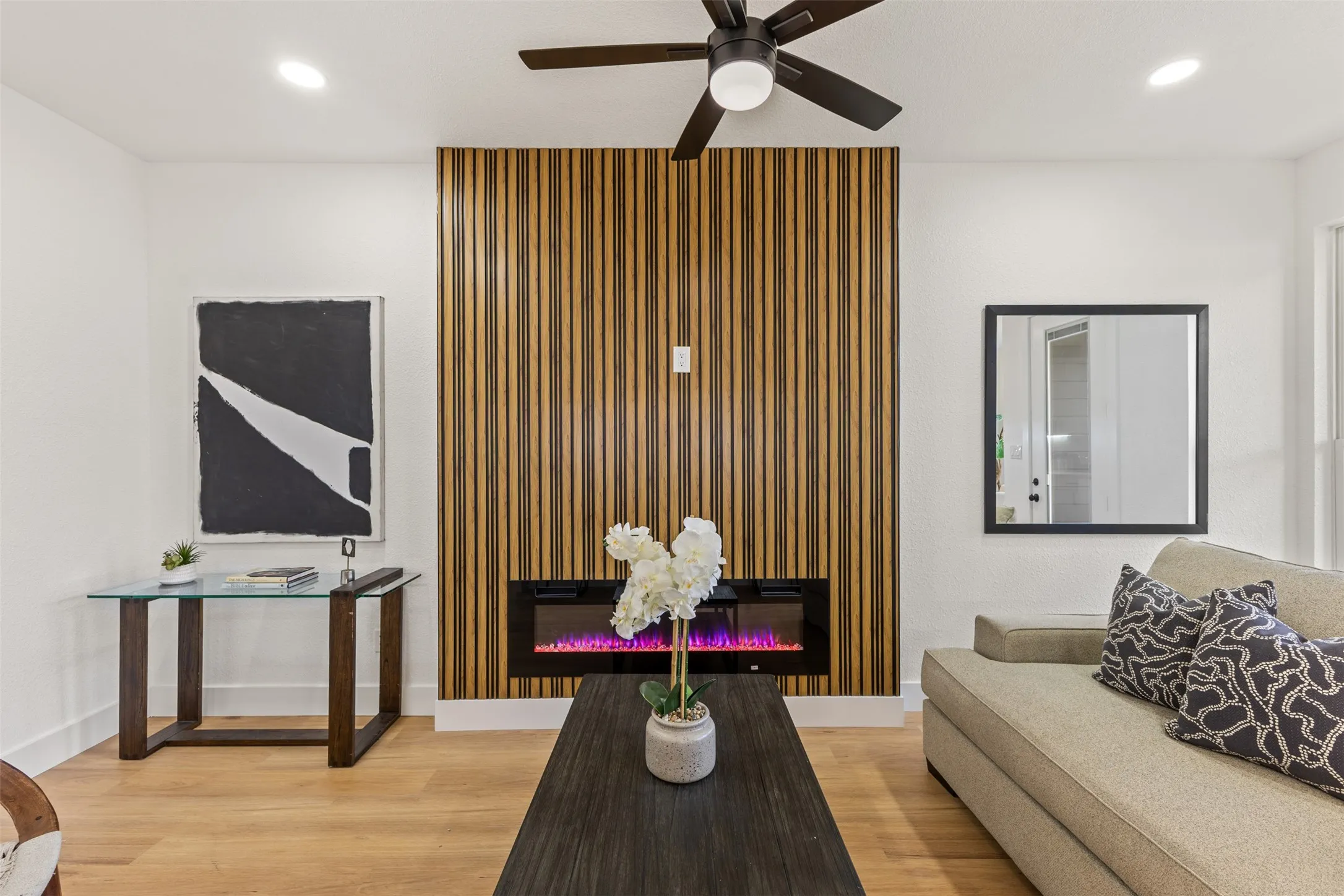 Living room featuring a glass covered fireplace, light wood finished floors, recessed lighting, and a ceiling fan