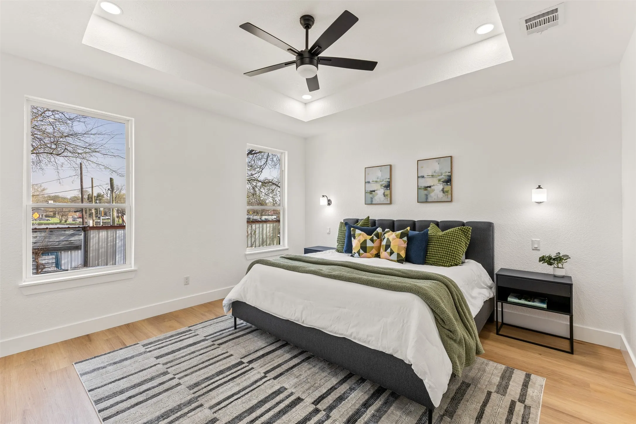 Bedroom featuring light wood finished floors, a ceiling fan, recessed lighting, and a tray ceiling