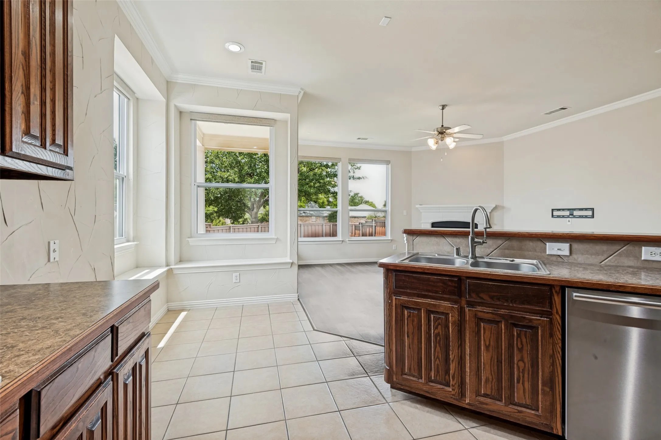 Kitchen has easy keep tile flooring, dark wood-finish cabinetry, and a stainless steel sink with a gooseneck faucet.