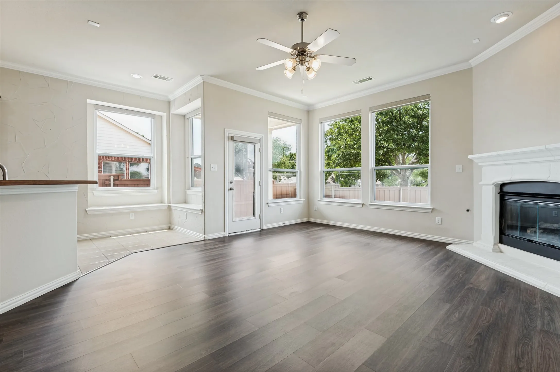 Open-concept living space featuring luxury vinyl plank flooring and multiple large windows.  Covered patio access from here.