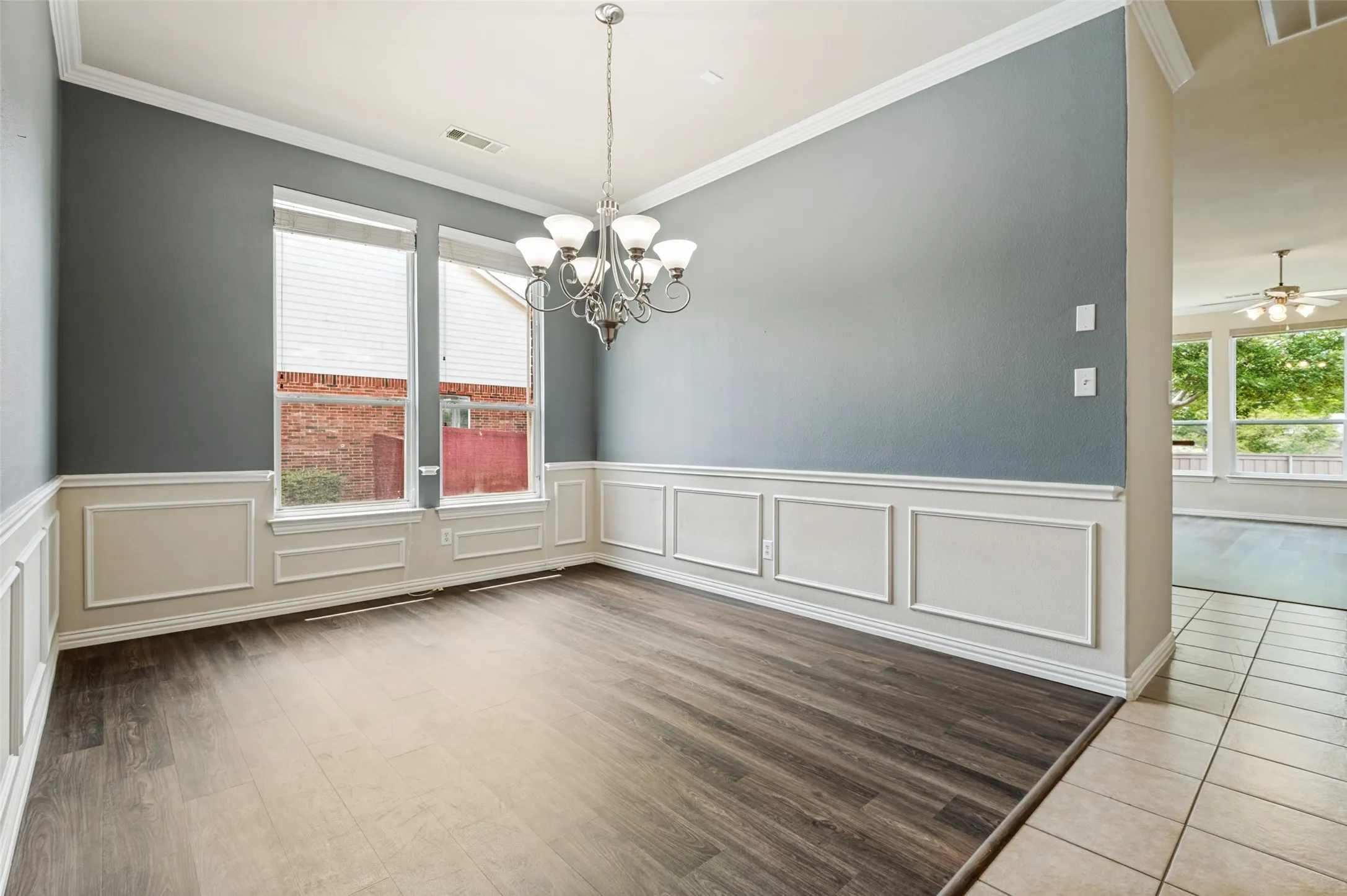 Elegant formal dining room with picture frame wainscoting, large chandelier, towering windows!