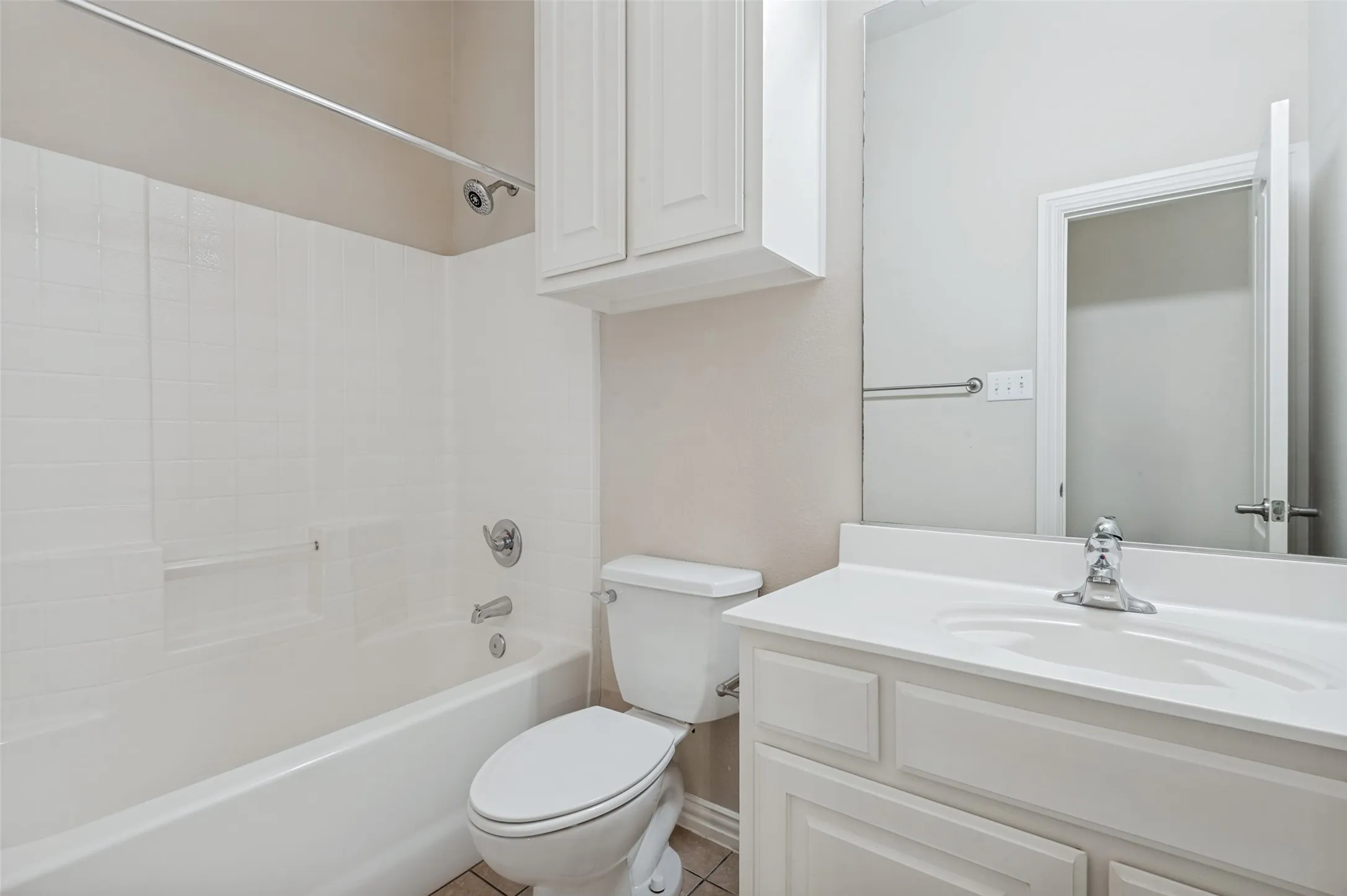 Full bathroom featuring a white vanity with integrated sink, chrome faucet, wall-mounted mirror, and white tub with tiled surround