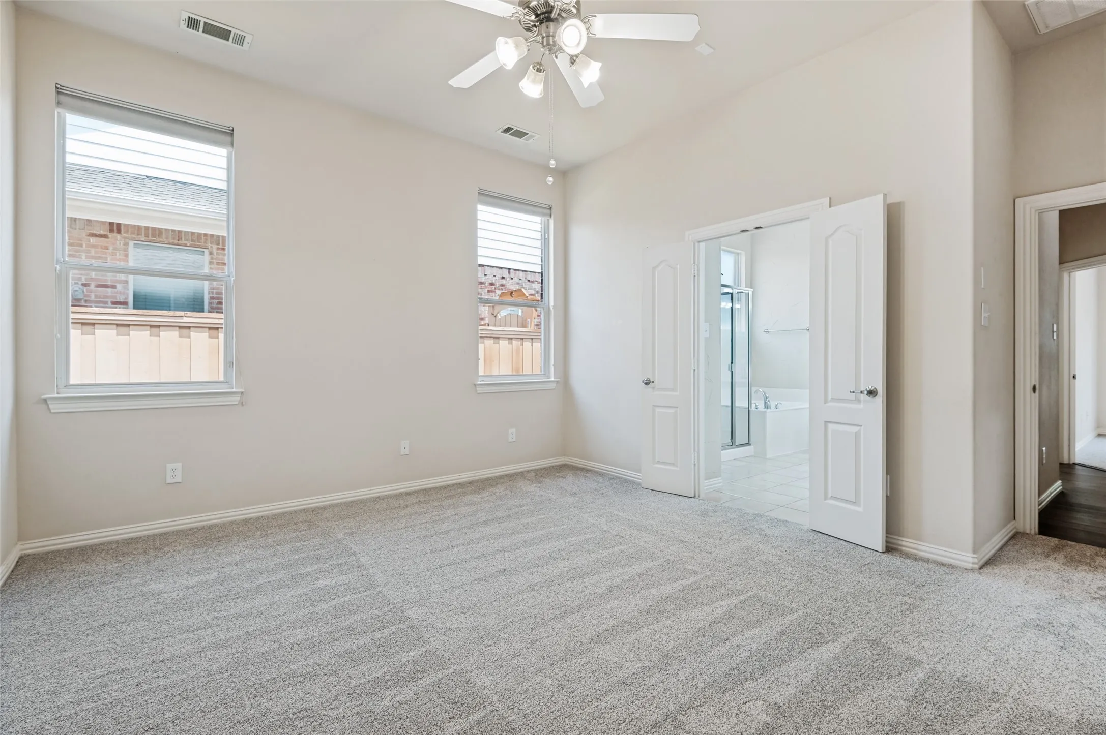 Spacious room featuring high ceilings and new carpet installed in April. Perfect location for a king size bed between the two windows! Primary bedroom located on the quiet backside of the home.