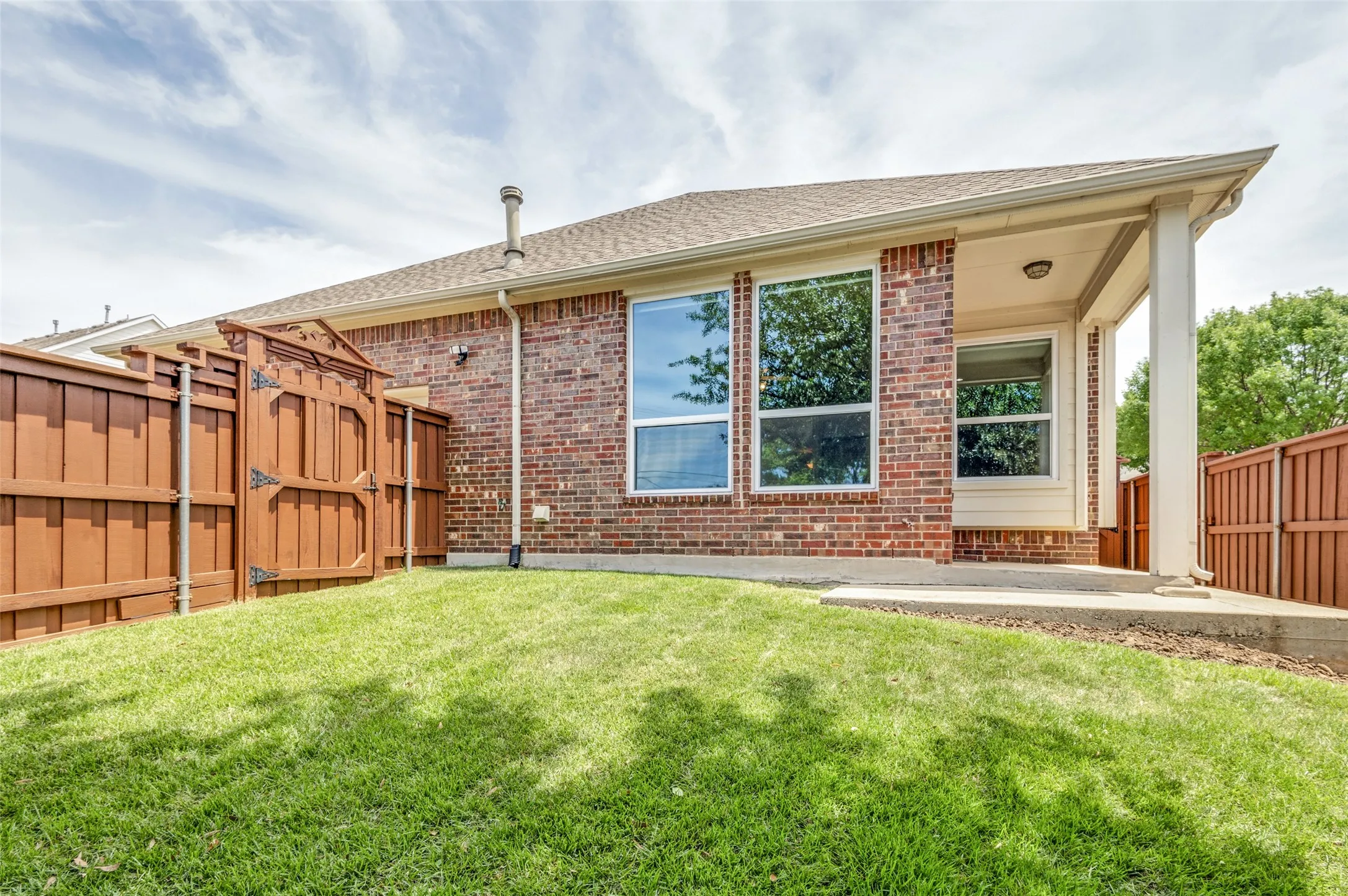 Expansive green lawn providing outdoor space with beautiful gates and view of the covered patio.