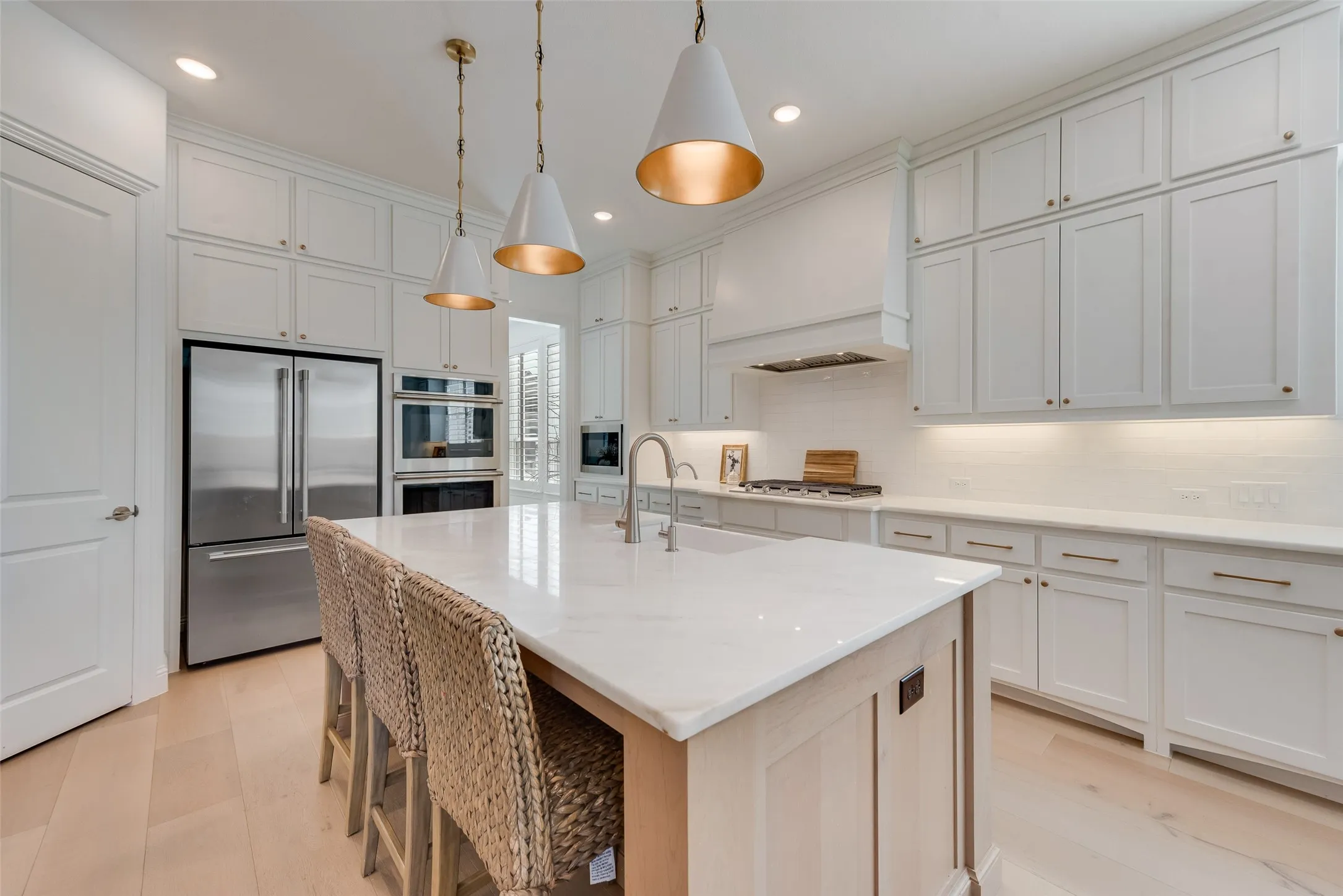 Decorative lighting, floor to ceiling cabinets, gas cooktop, and double ovens.
