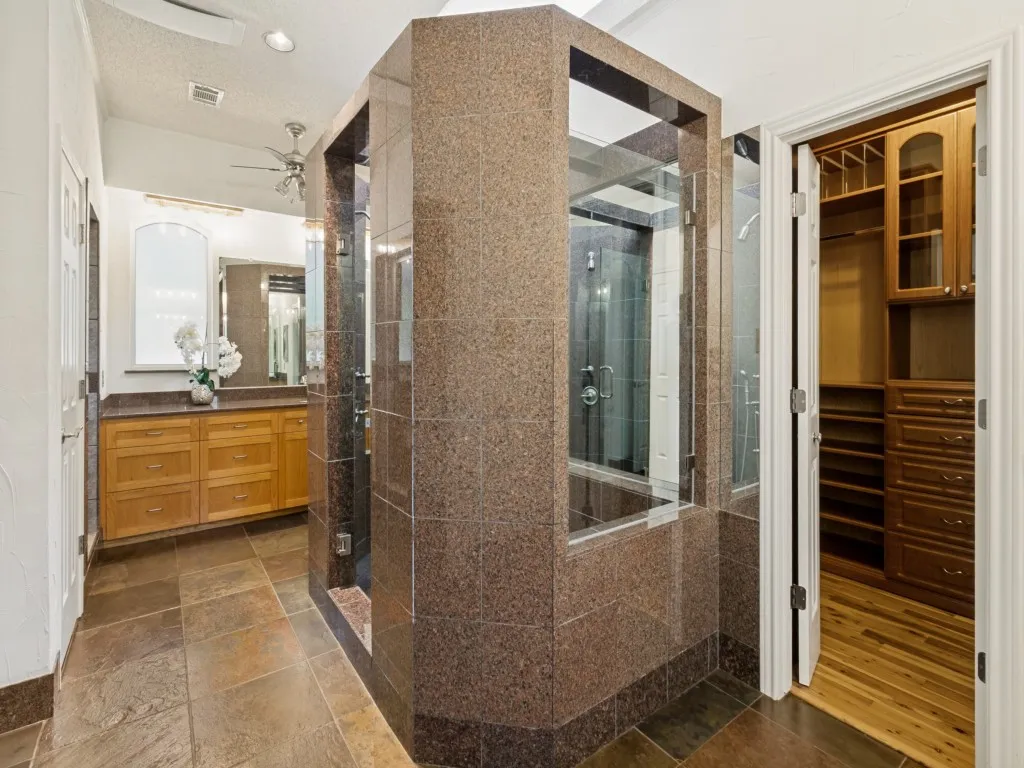 Finished with slate floors and granite baseboards, the spa-inspired primary bath offers dual vanities, a spacious glass-and-granite double shower, and custom his-and-hers closets!