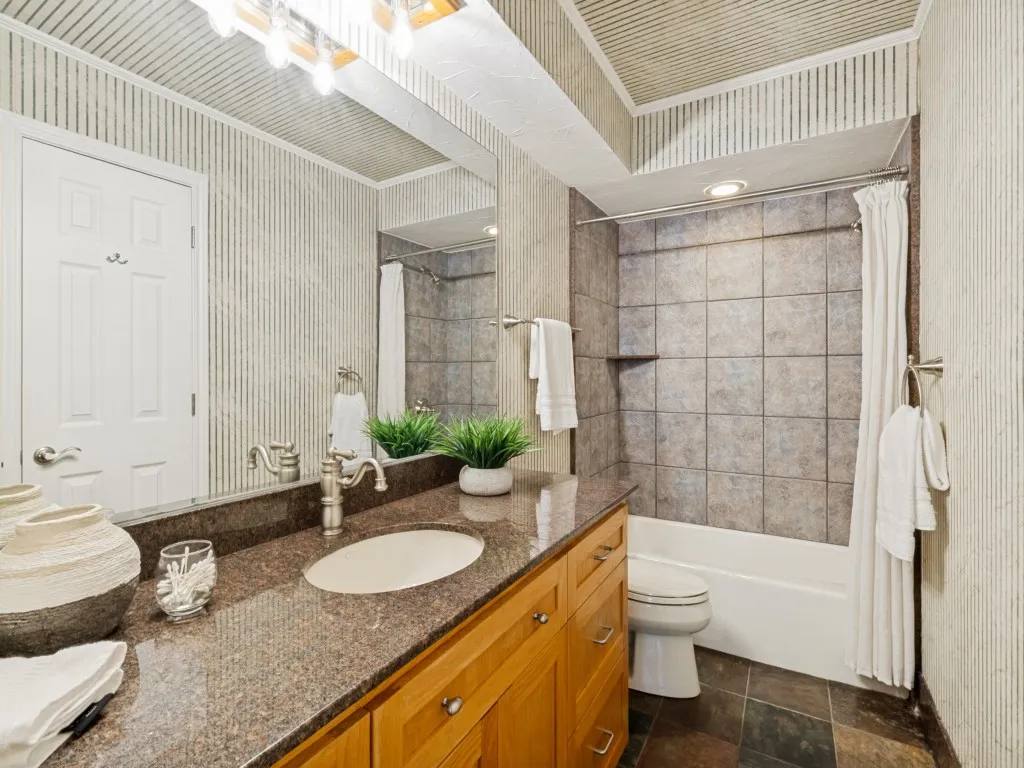 The shared full bath is appointed with granite counters, custom red oak cabinetry, and slate floors!