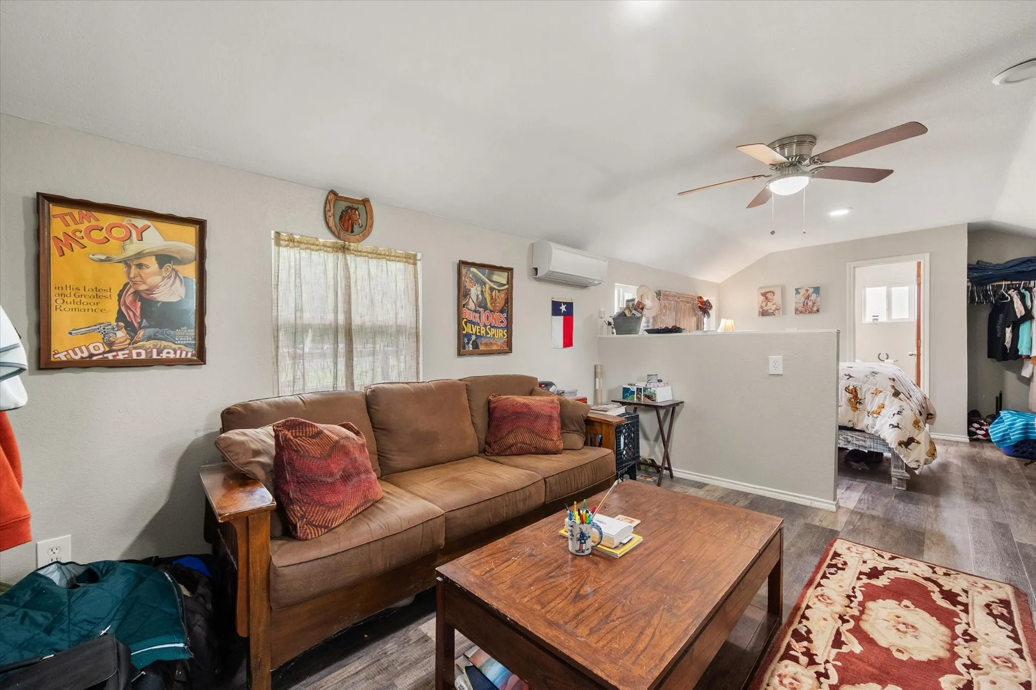 Living area featuring wood-finish flooring, a vaulted ceiling with a ceiling fan, and a mini-split HVAC unit