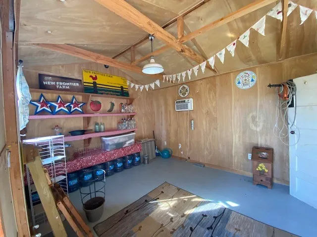 Interior space featuring wood-finish wall panels, exposed ceiling rafters, and a light-toned floor