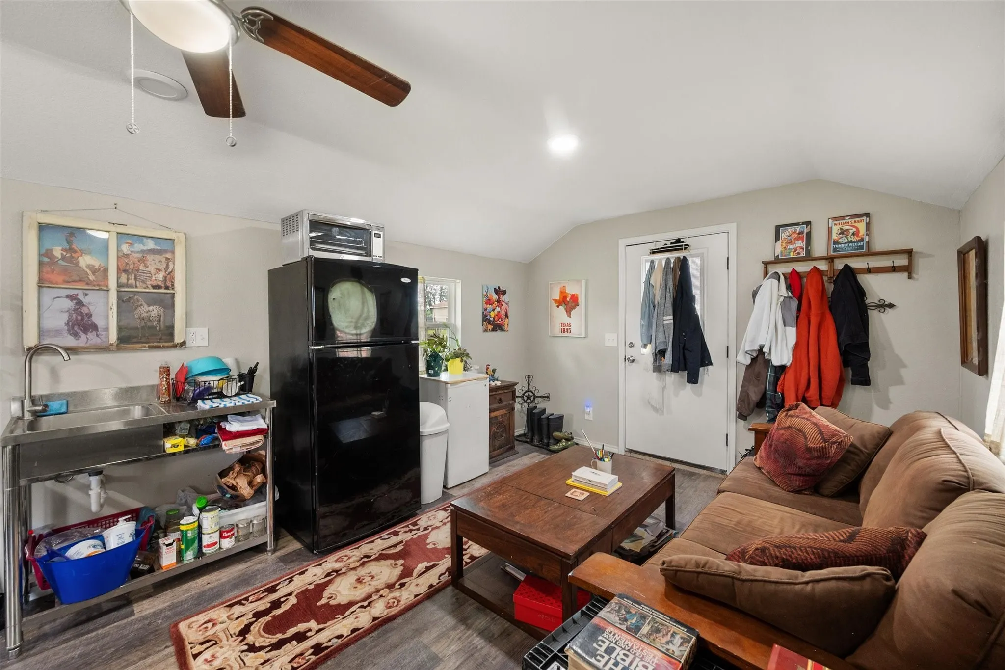 Open-concept living area with wood-finish flooring, a stainless steel utility sink, and a high vaulted ceiling