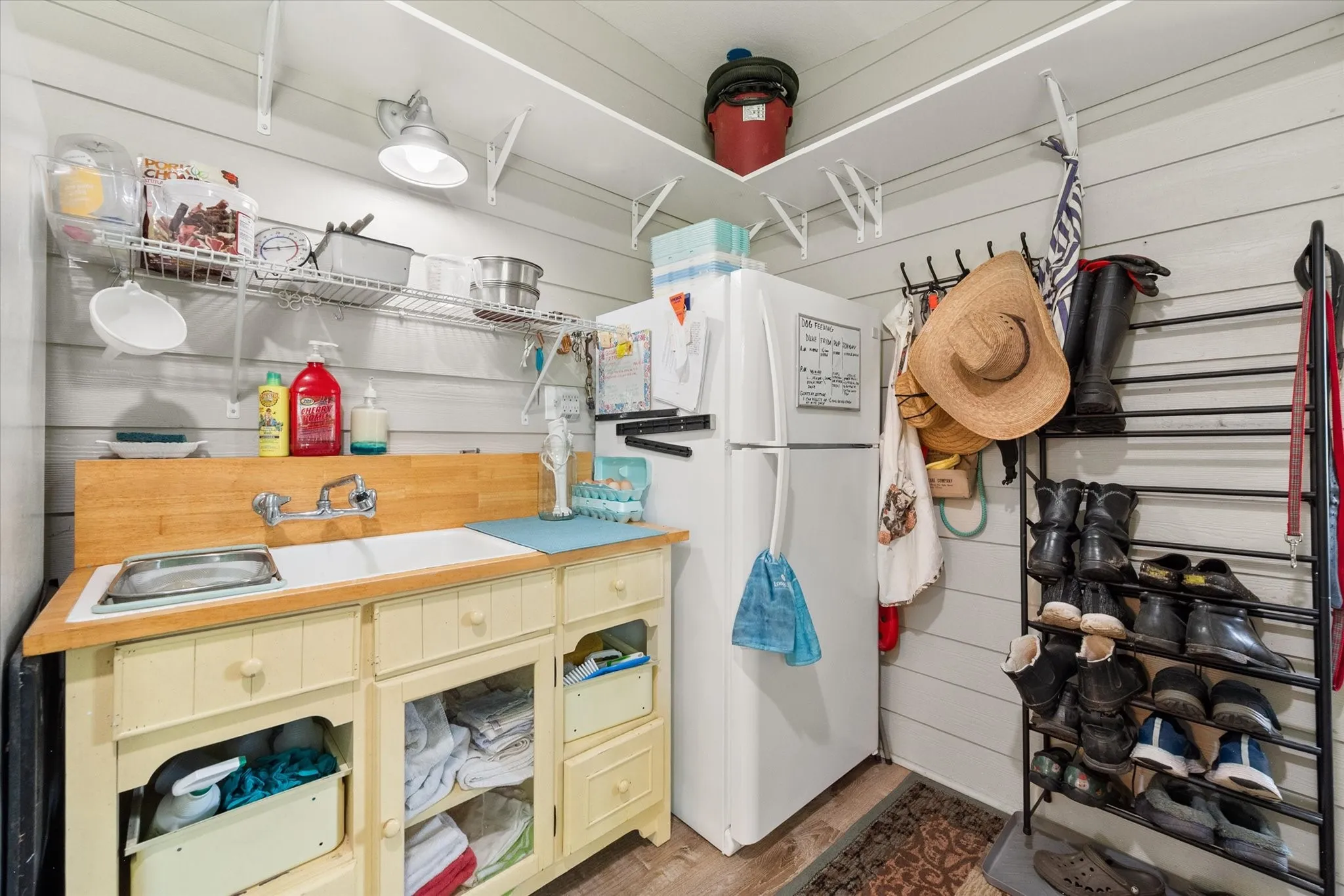 Utility room featuring a built-in double basin sink, wood-finish countertop, and ample open and closed storage cabinetry