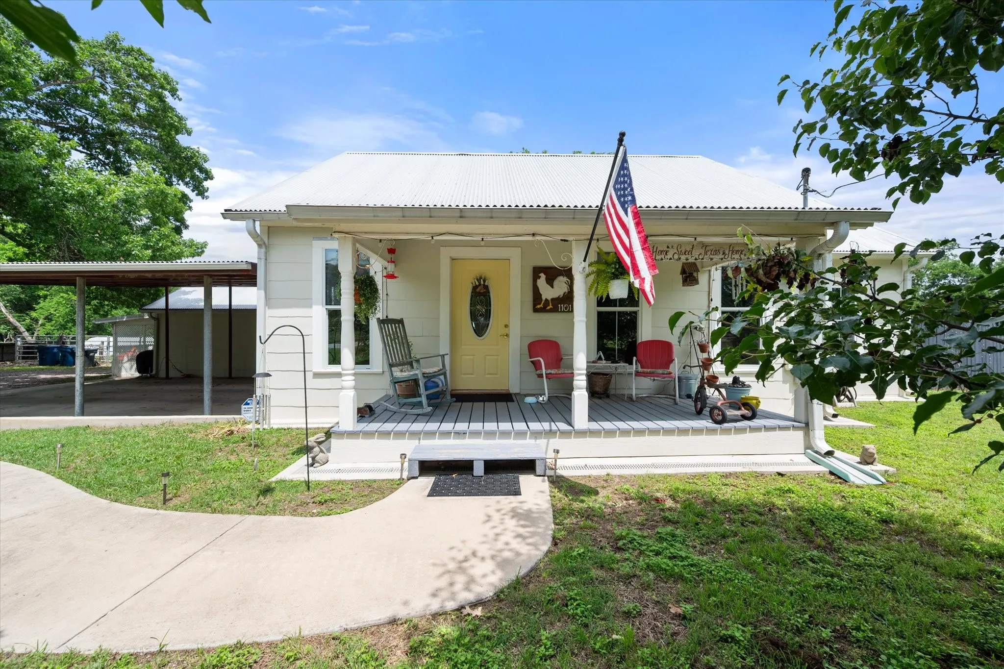 Light-colored siding exterior featuring a white corrugated metal roof and a full-width covered front porch