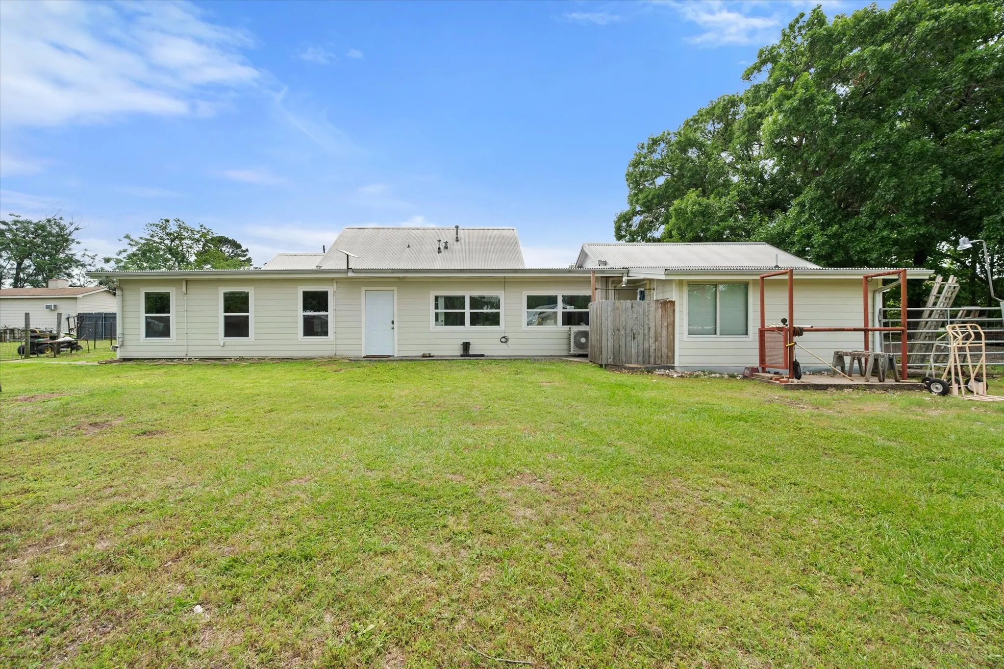 Expansive rear yard featuring a grass lawn and exterior property wall with multiple windows and a door