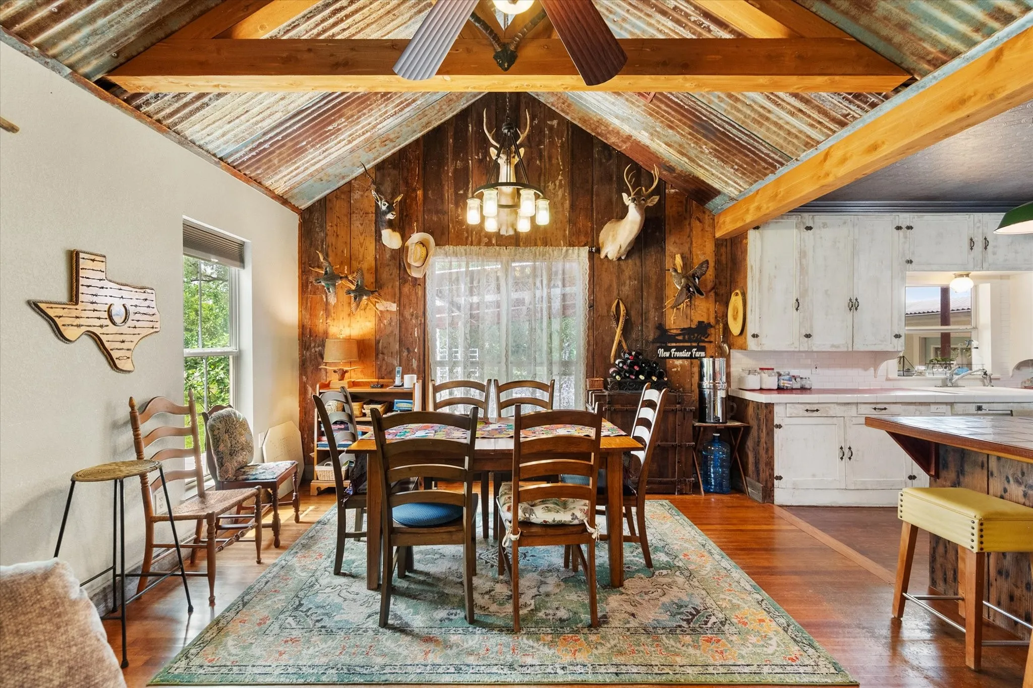 Dining area featuring a vaulted corrugated metal ceiling and exposed wood beams