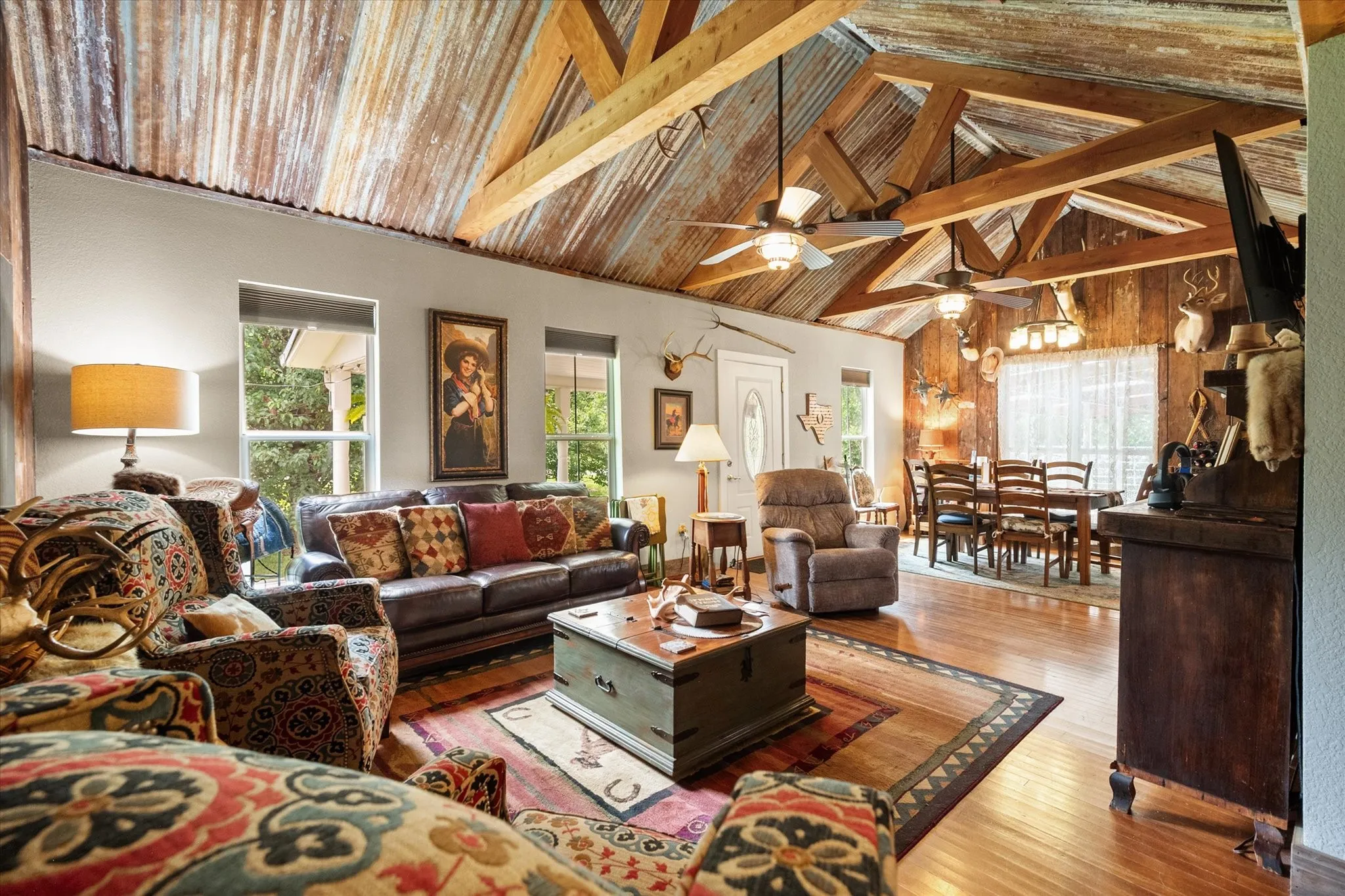 Open-concept living space with vaulted corrugated metal ceilings and exposed wood beams